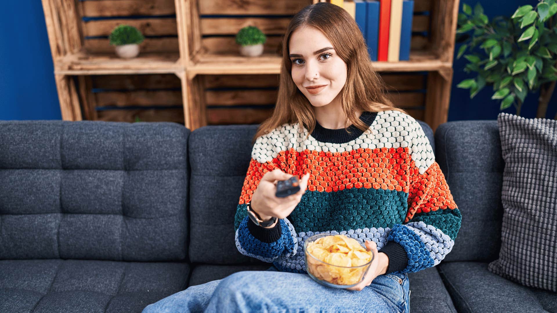 smiling woman watching television with popcorn