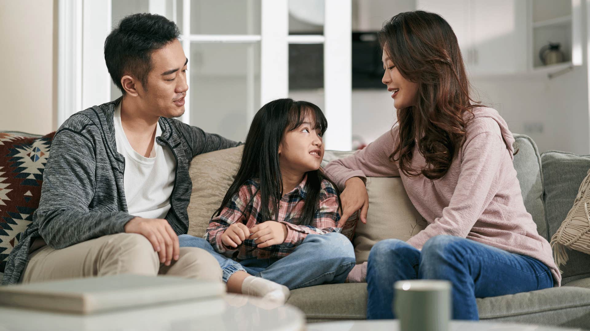 parents talking with daughter on couch