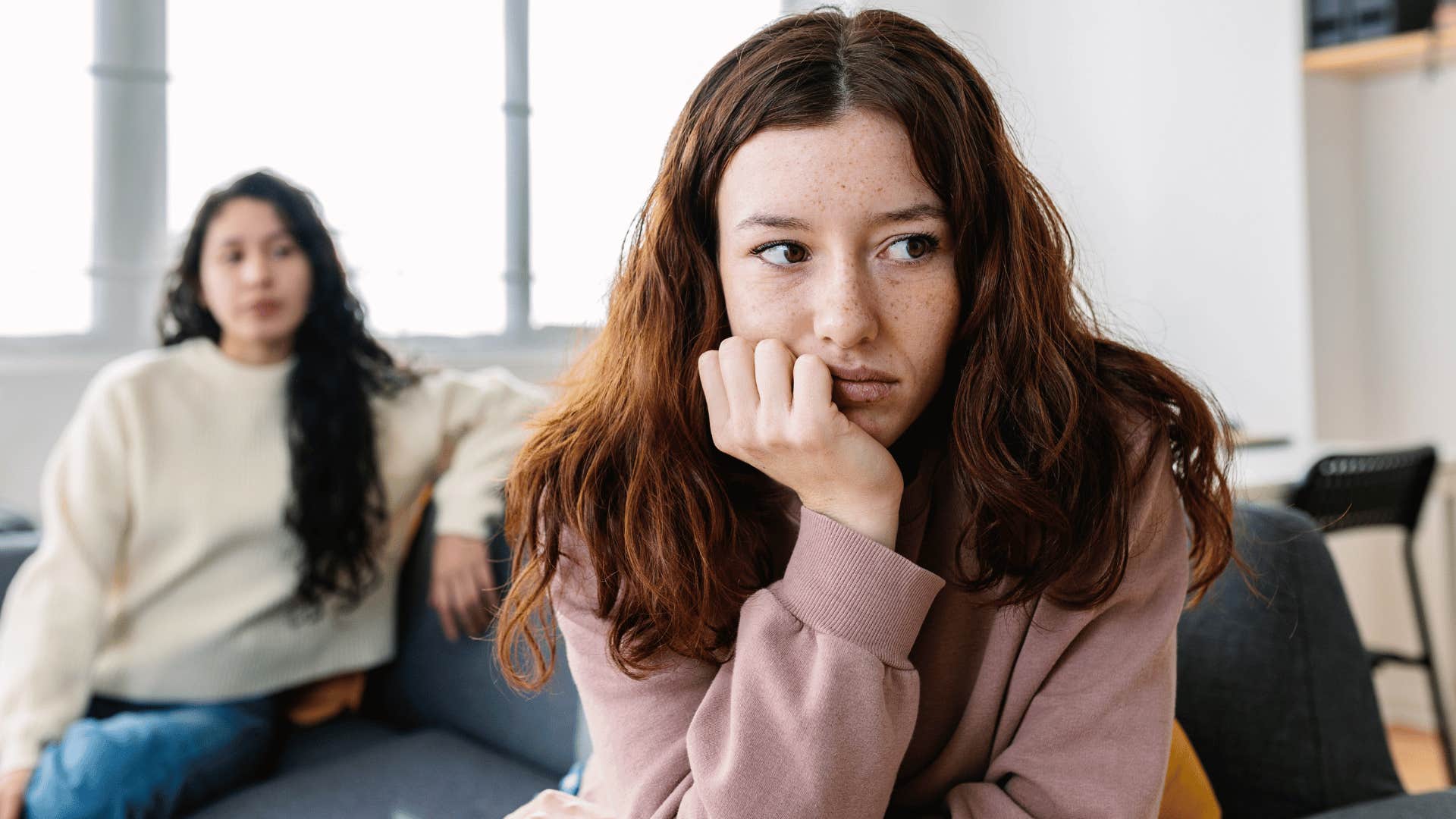 young woman turned away from friend she shares no interests with