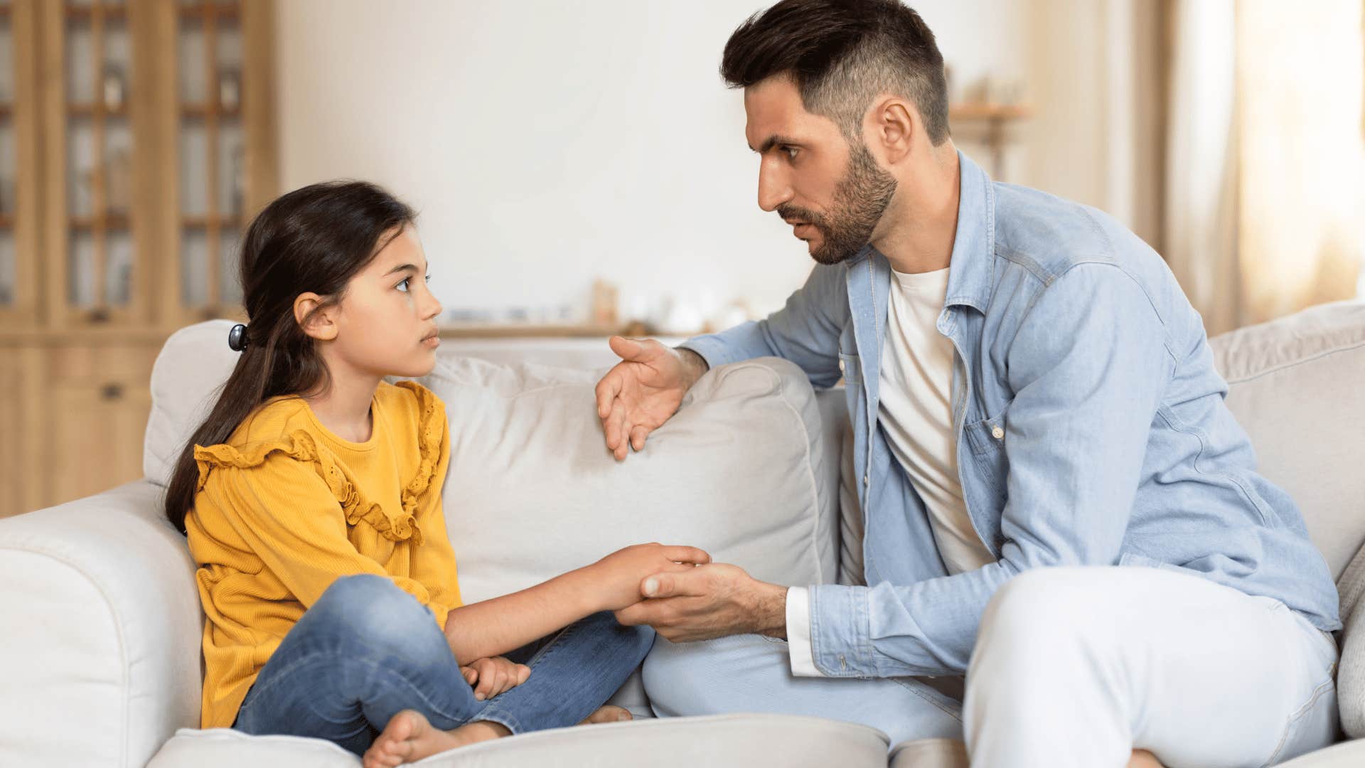 father talking to daughter on couch