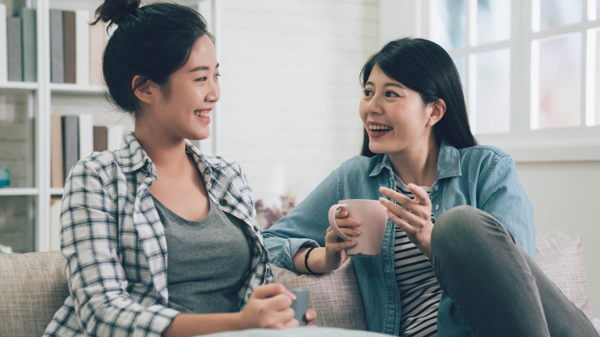 two smiling women talking on a couch