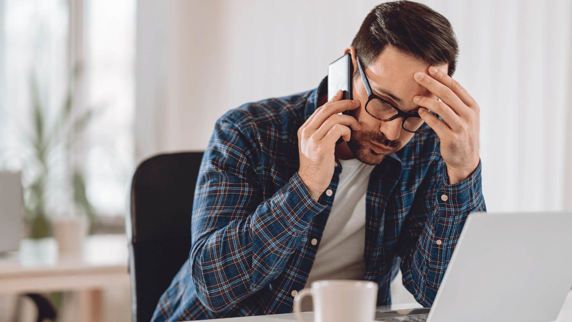 stressed man holding his forehead talking on phone