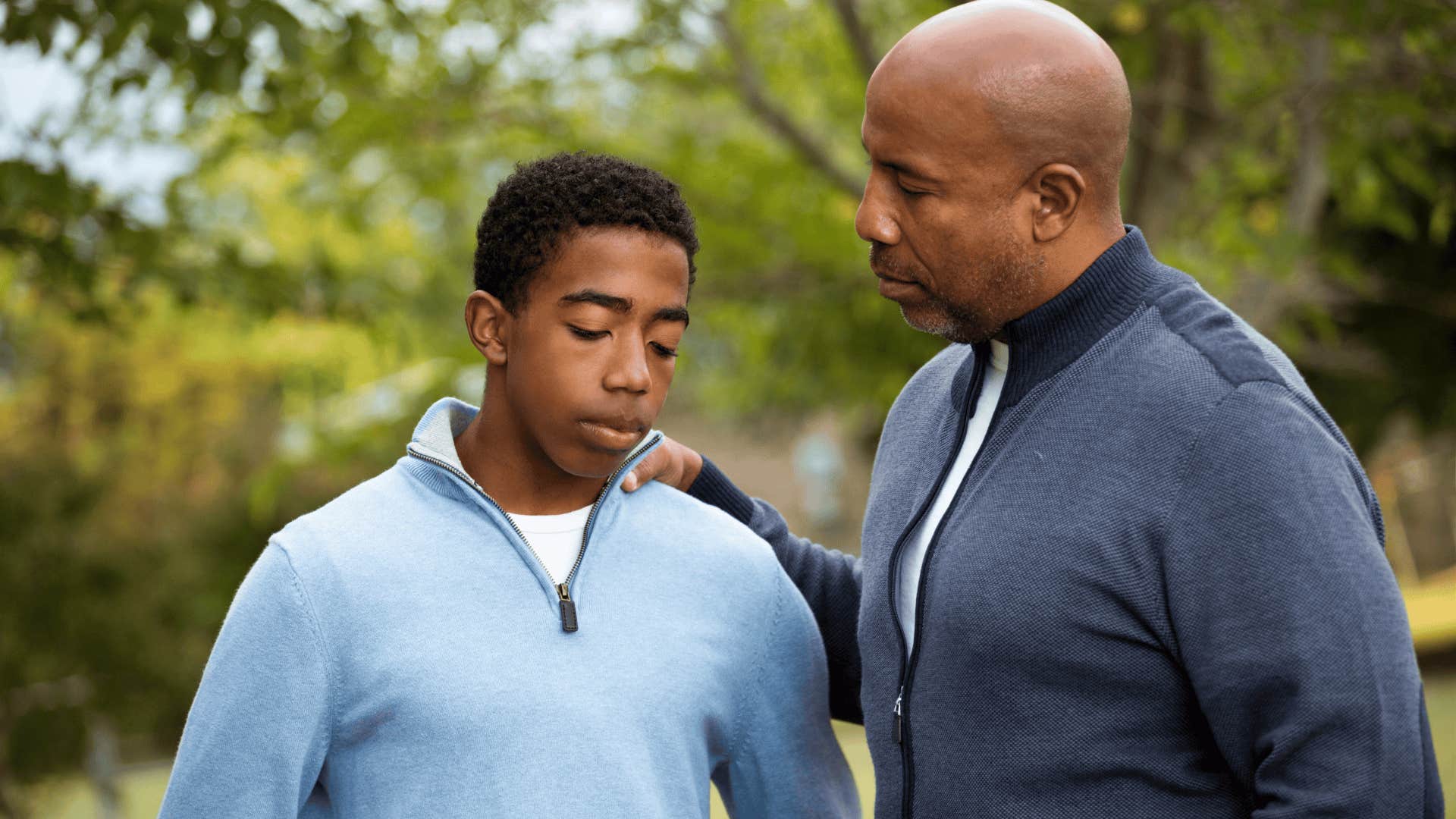 man comforting his upset teenage son