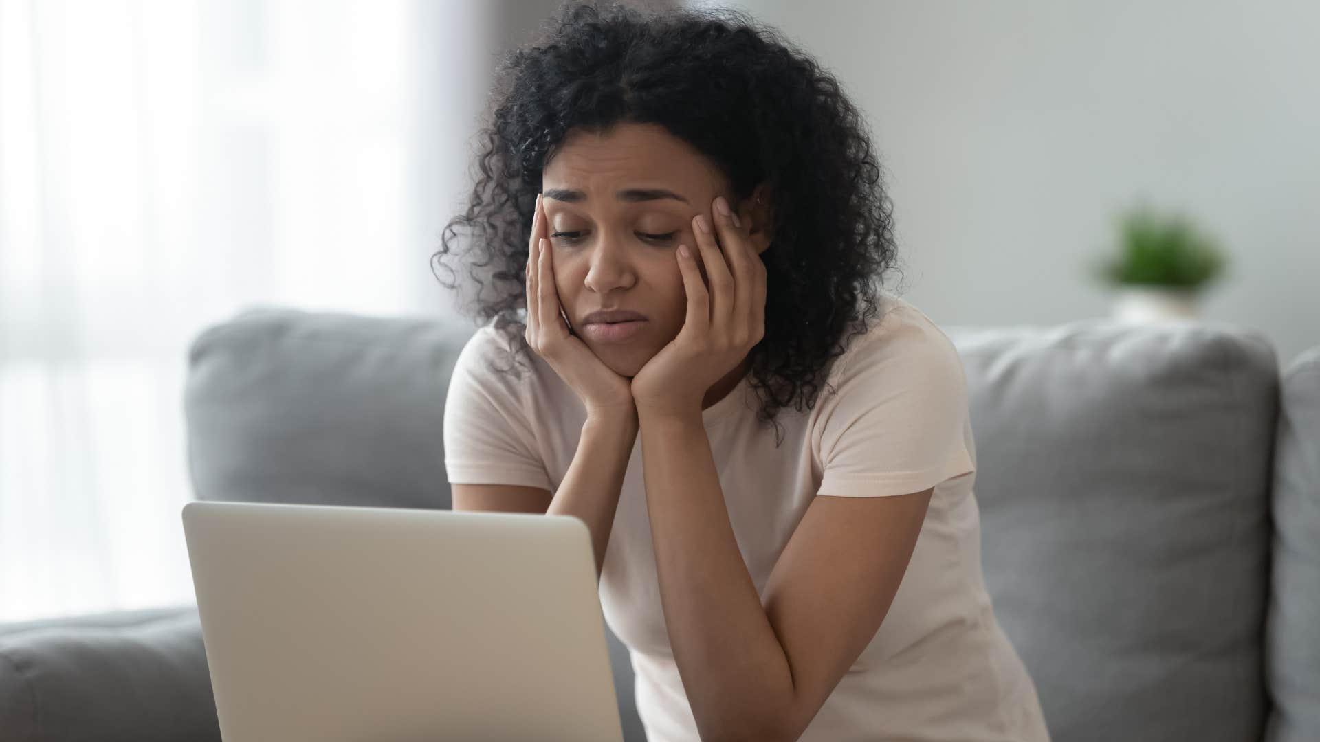 Sad Gen Z woman looking at her laptop