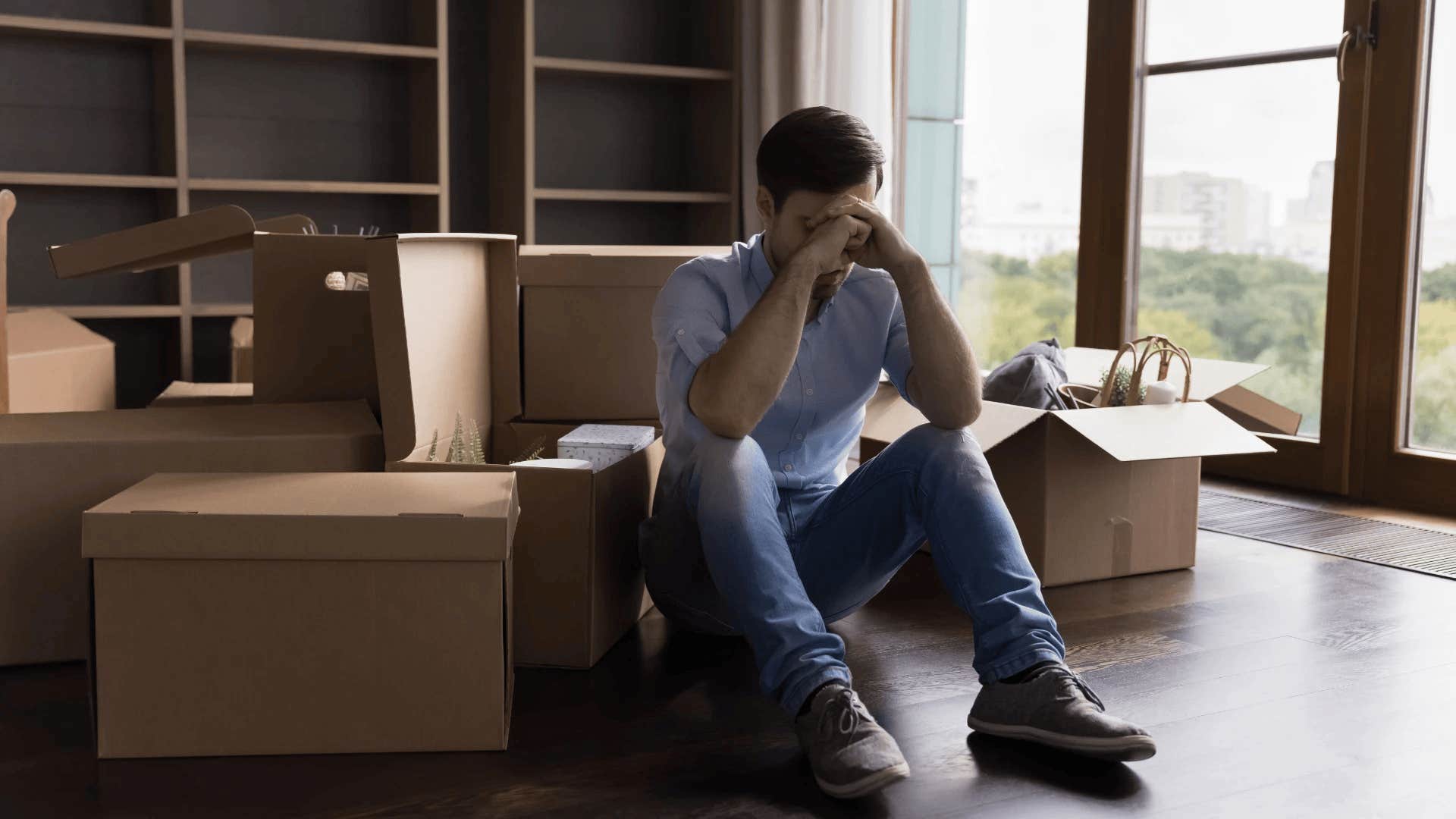 man sitting around empty boxes haunted by regrets that destroyed his marriage