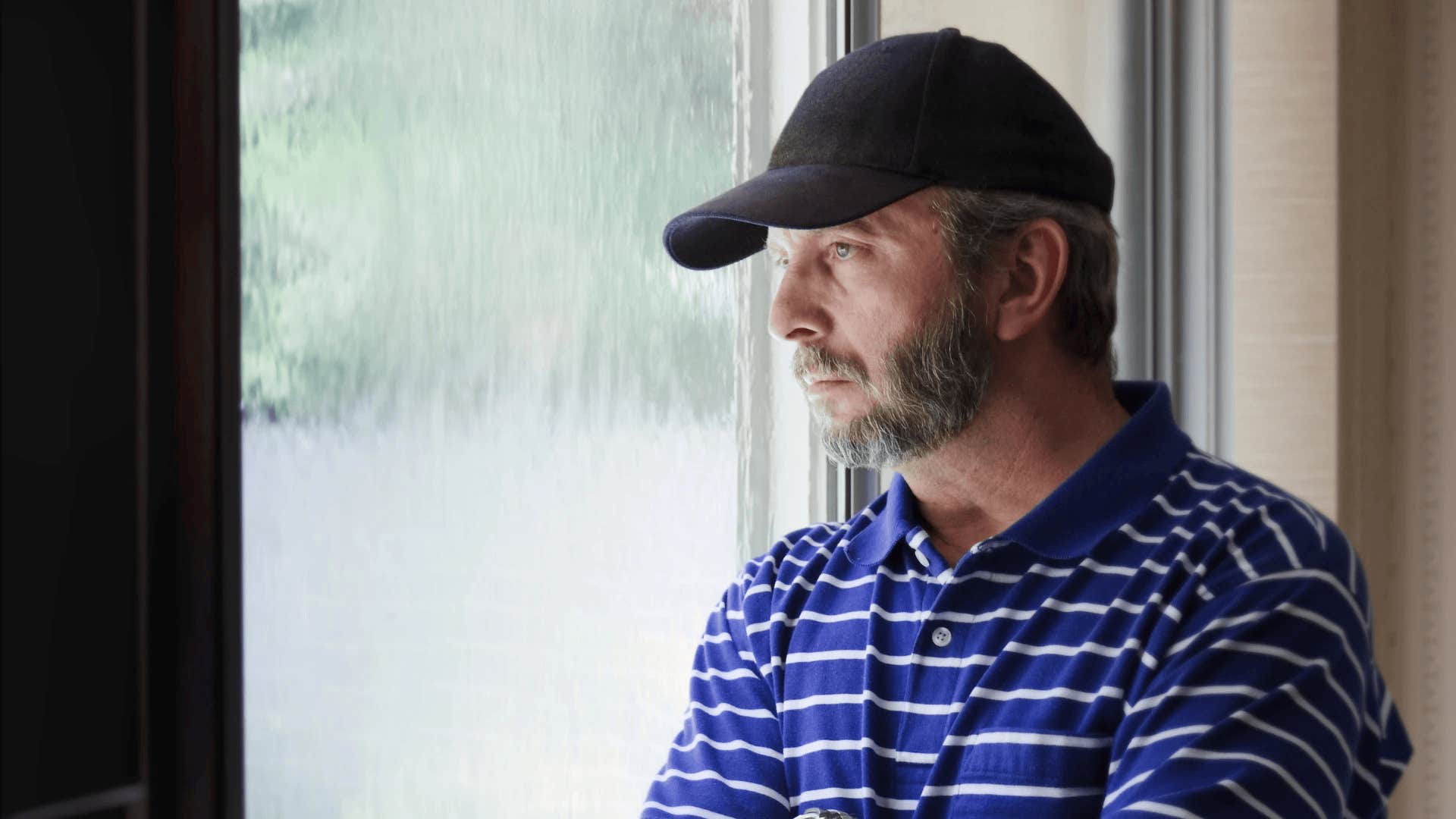 man staring out window haunted by regrets that destroyed his marriage