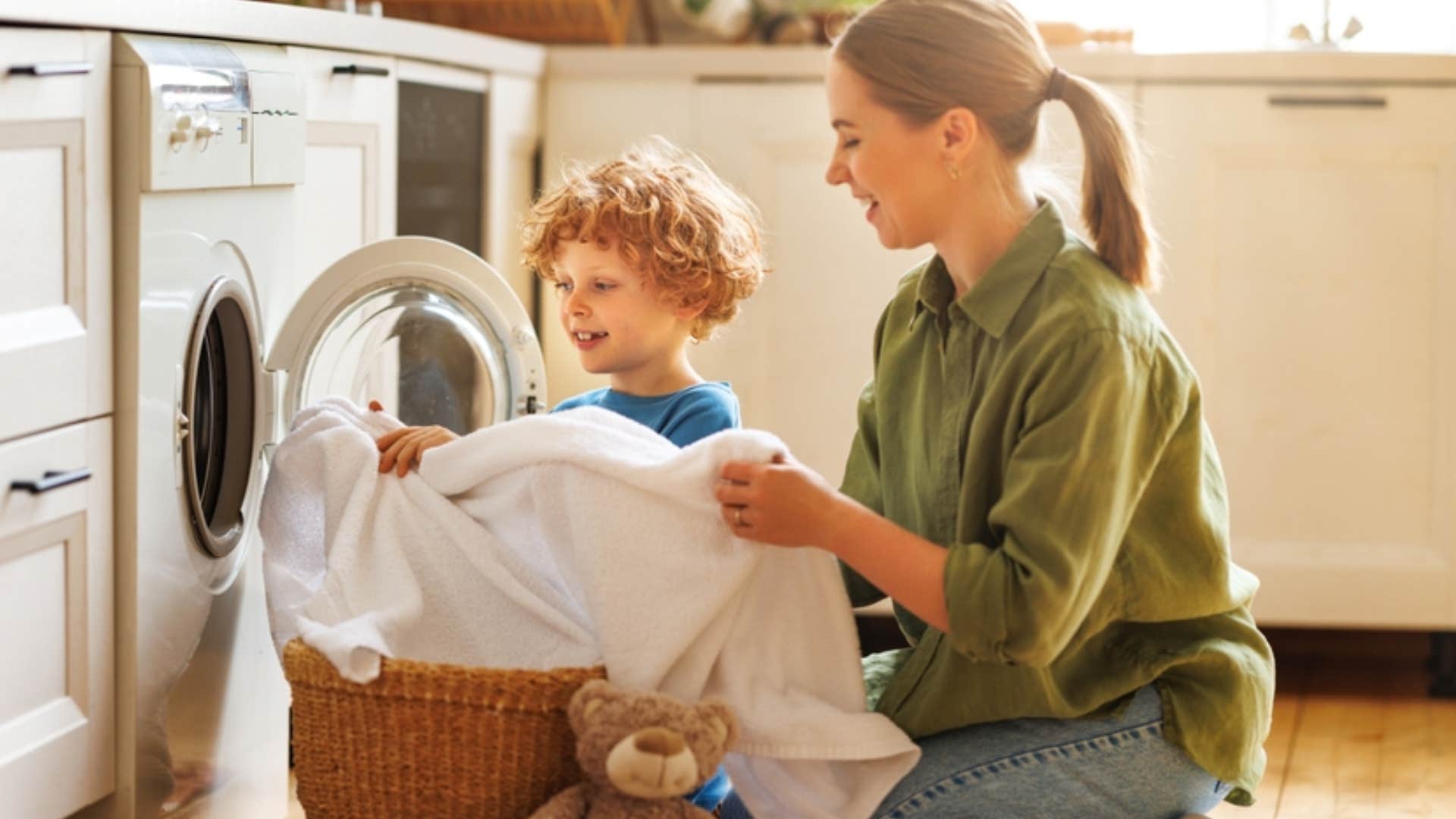 mom teaching young kid how to do his own laundry