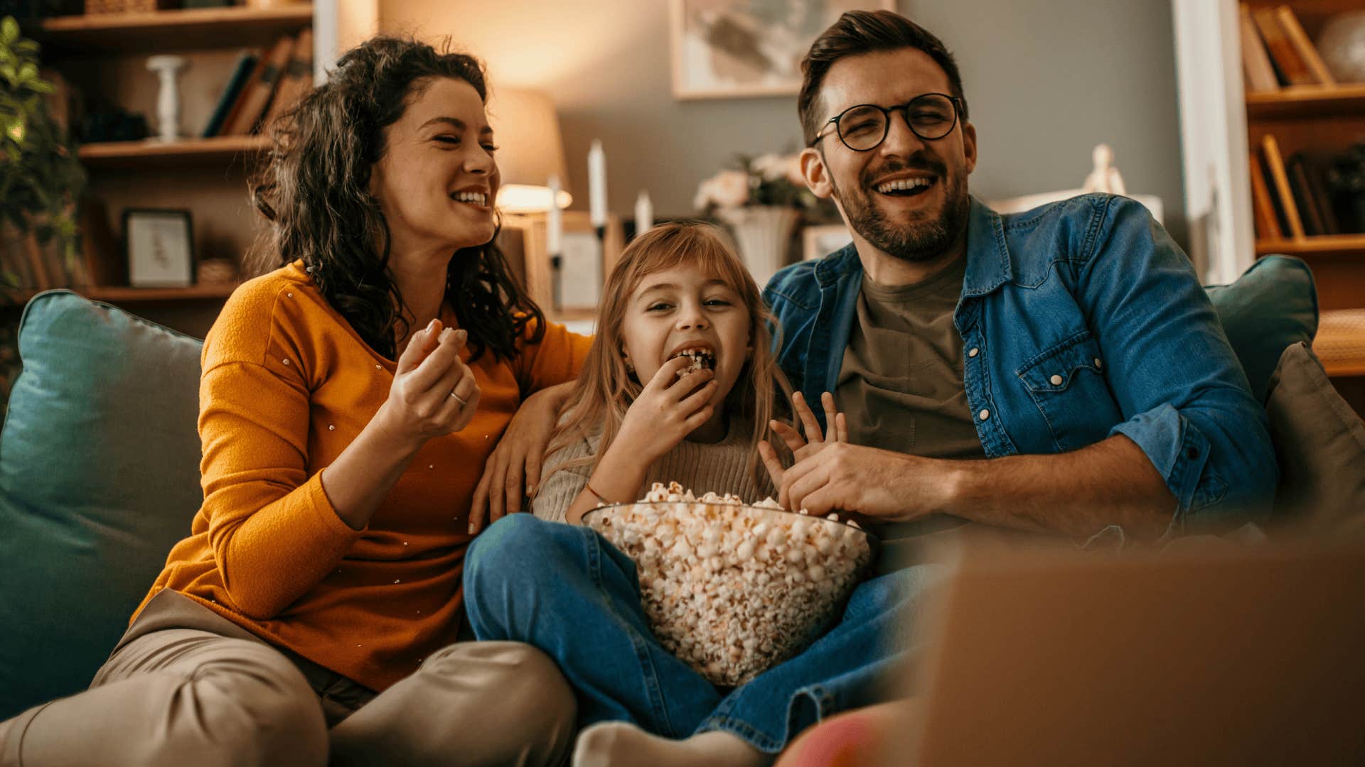 parents smiling and daughter watching a movie