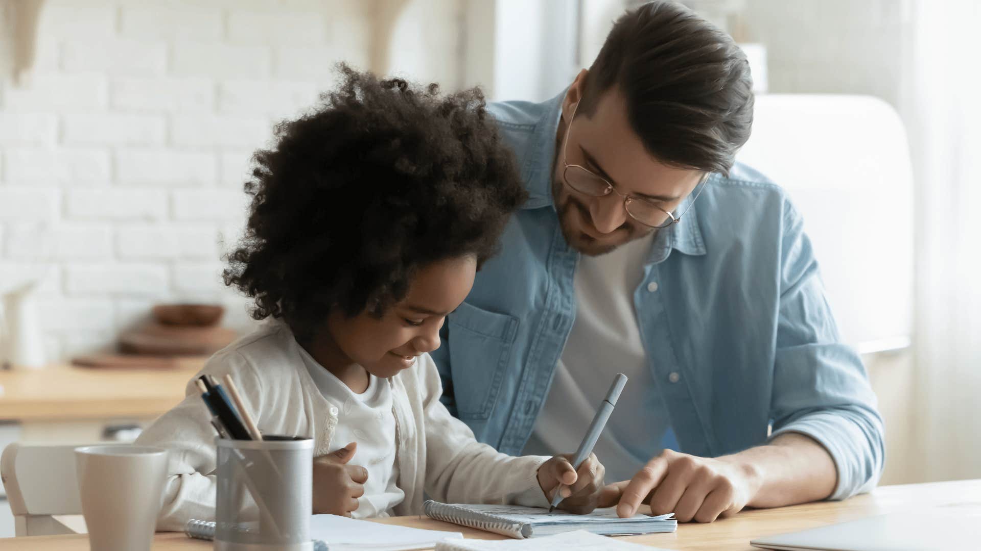 man writing a note with his young daughter
