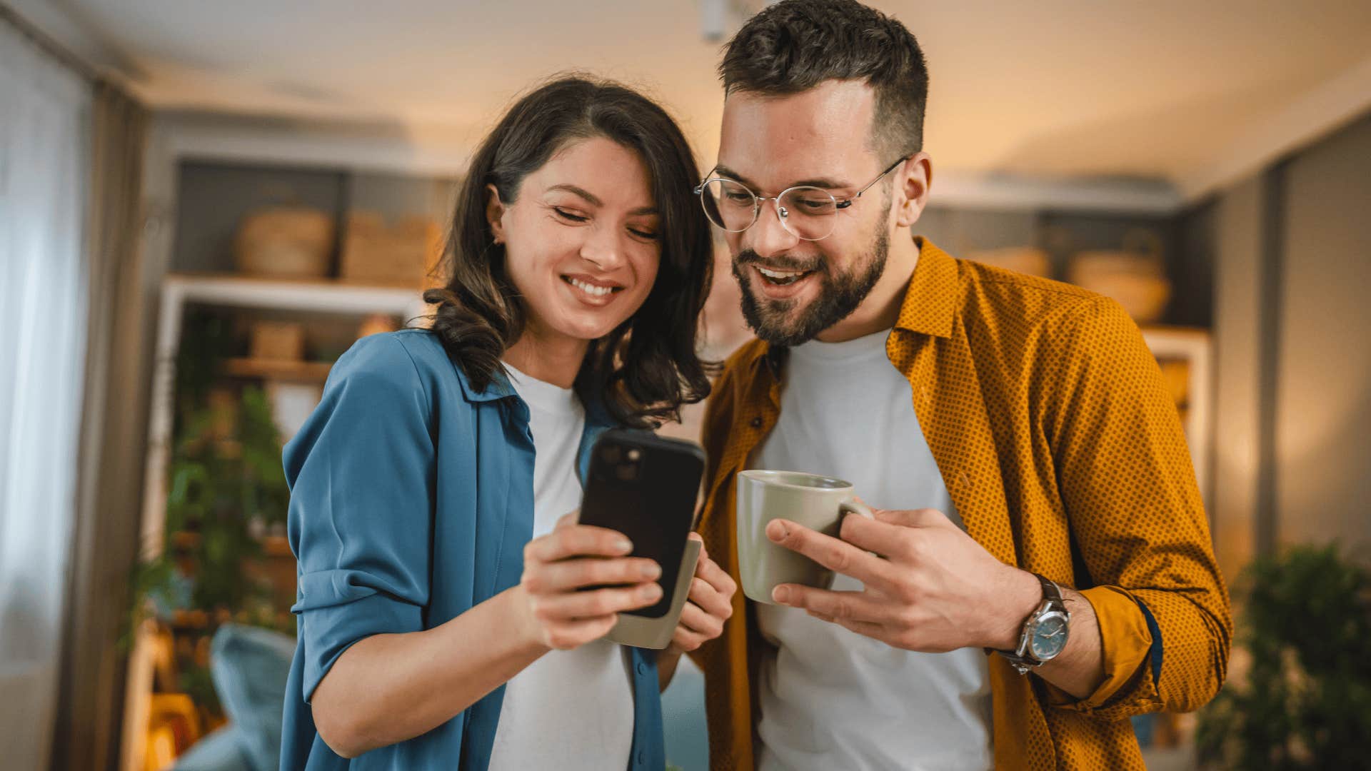 man and woman smiling looking at phone together