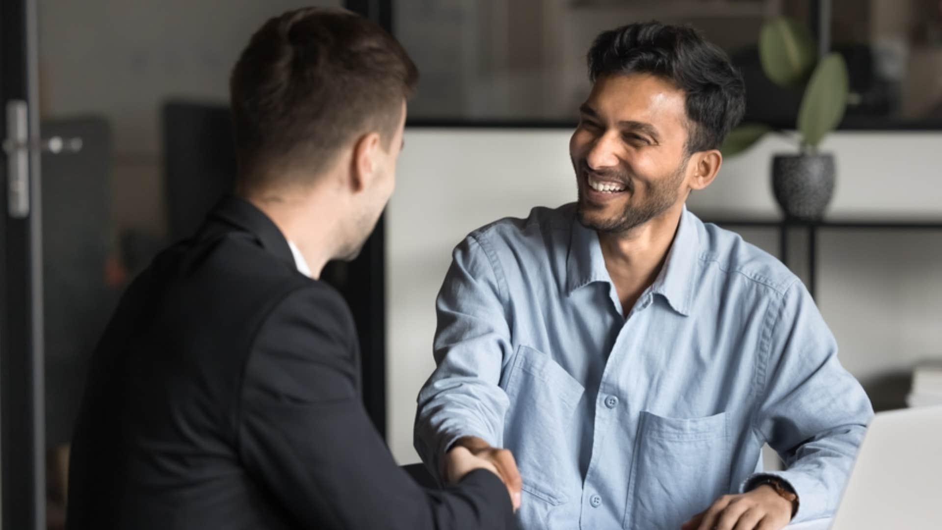 smiling man respectfully shaking hands with man