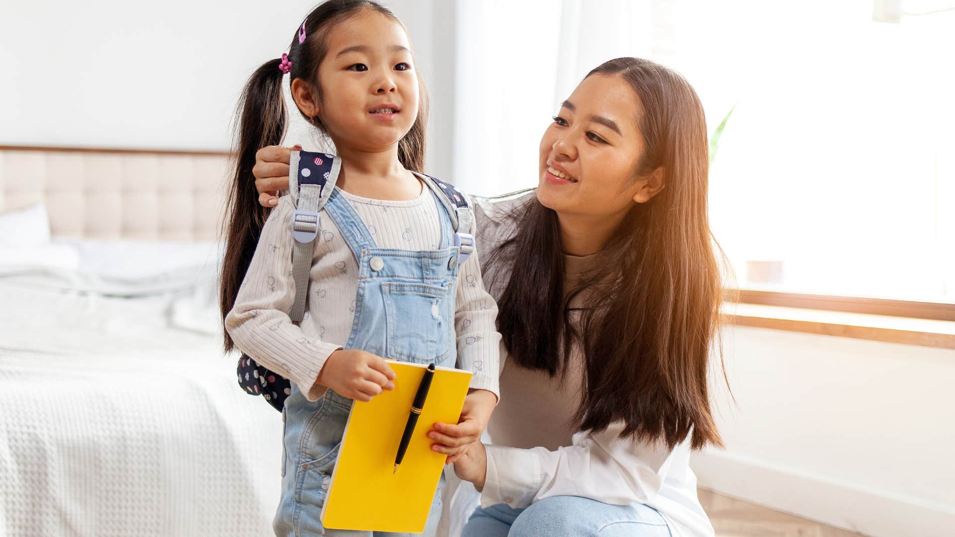 Gen X mom helping her daughter put on a backpack