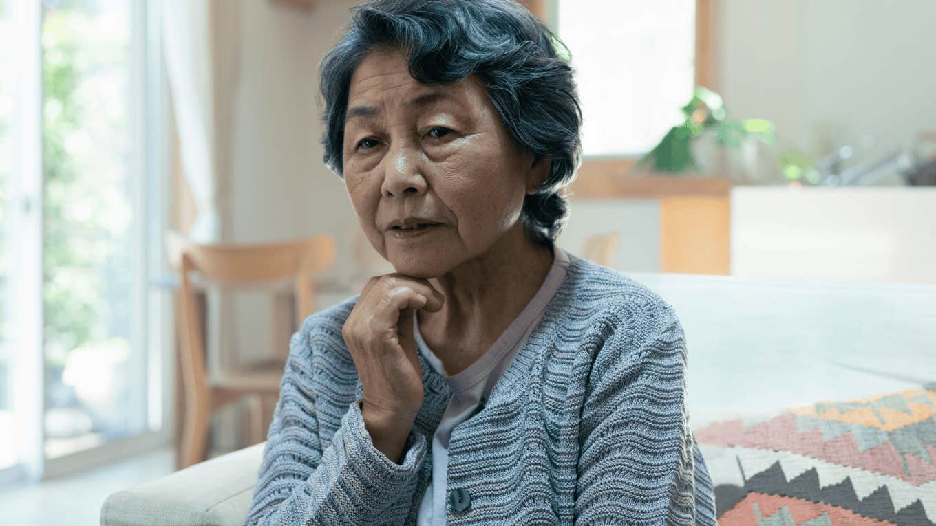 older woman looking sad holding her face