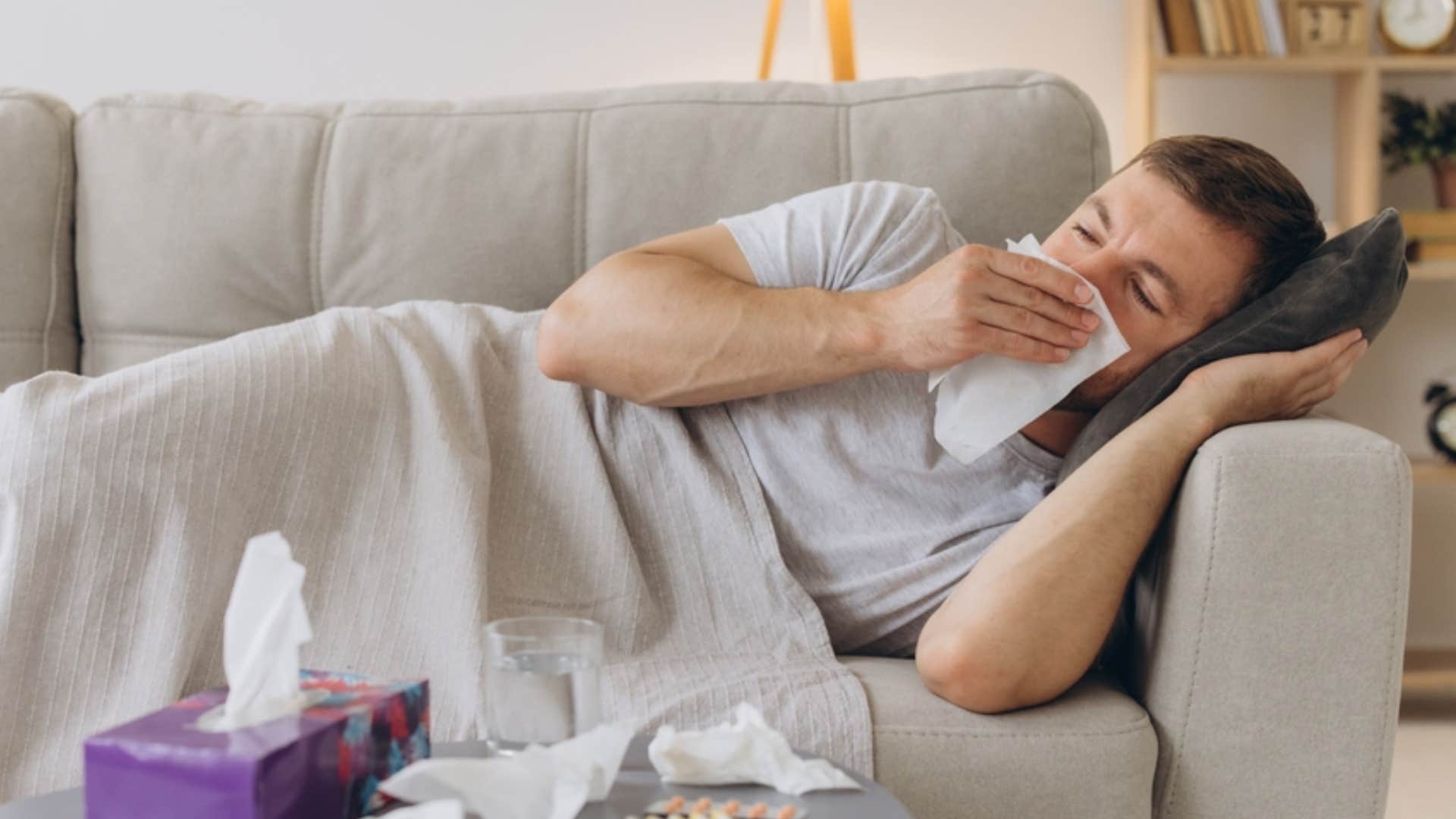 sick man blowing his nose on couch