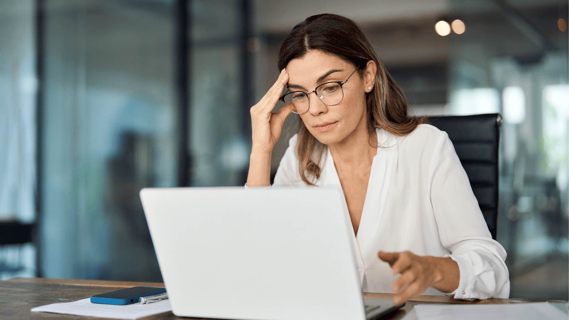 stressed woman sitting at her desk looking at laptop