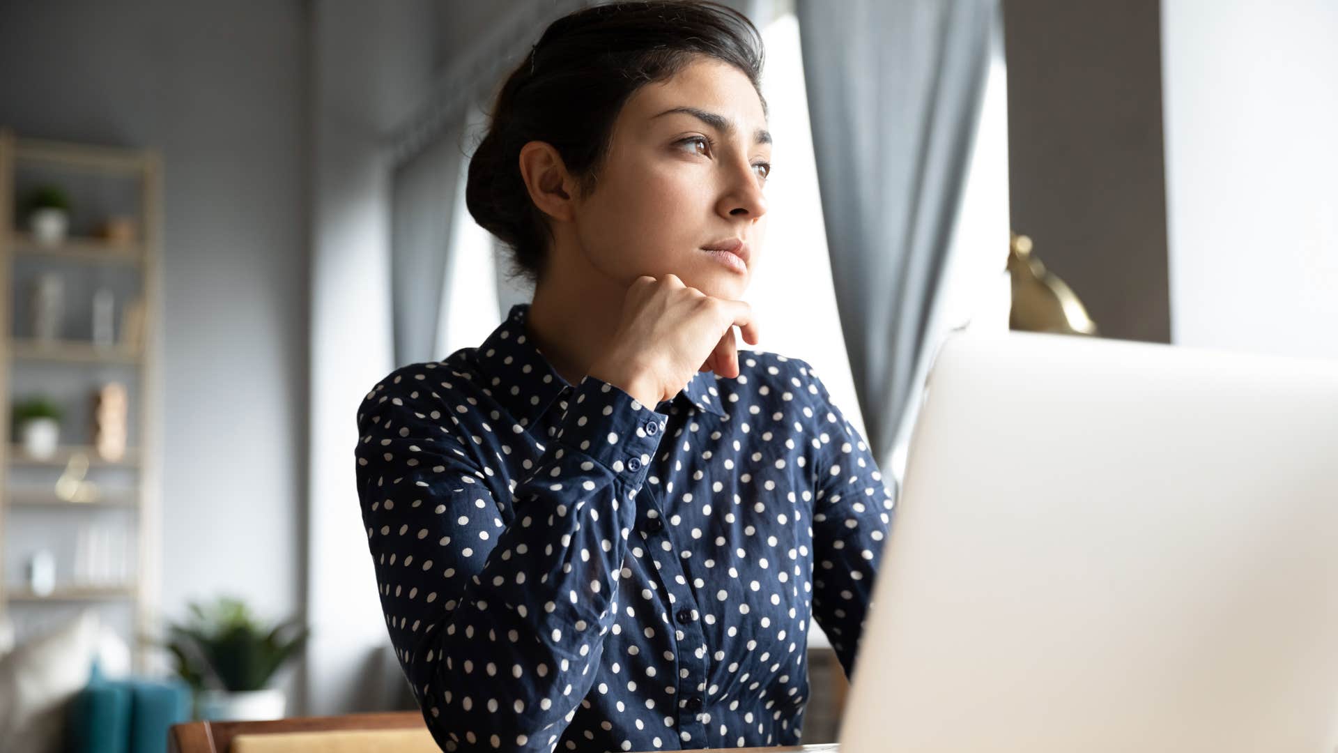 sad uninterested woman looking outside at work