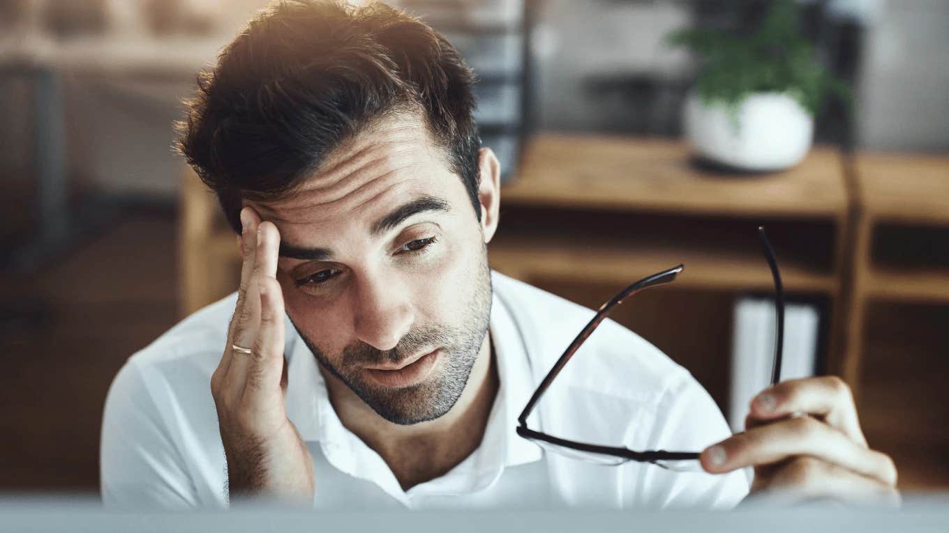 stressed worker holding his temple looking at laptop