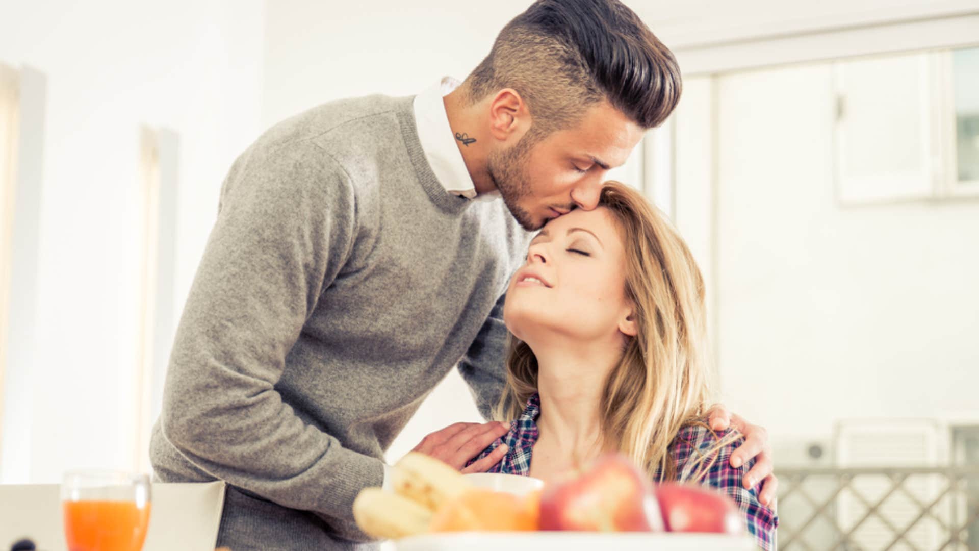 man kissing woman's head