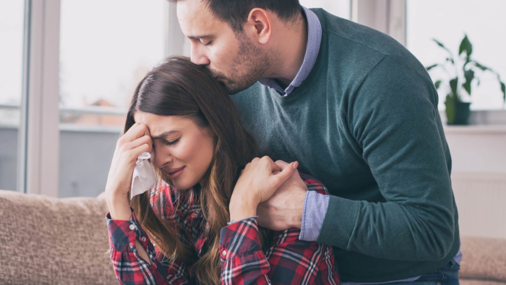 man kissing woman's head as she cries