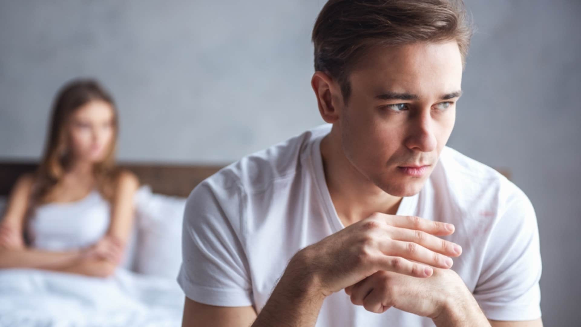 man turned away from woman sitting in bed