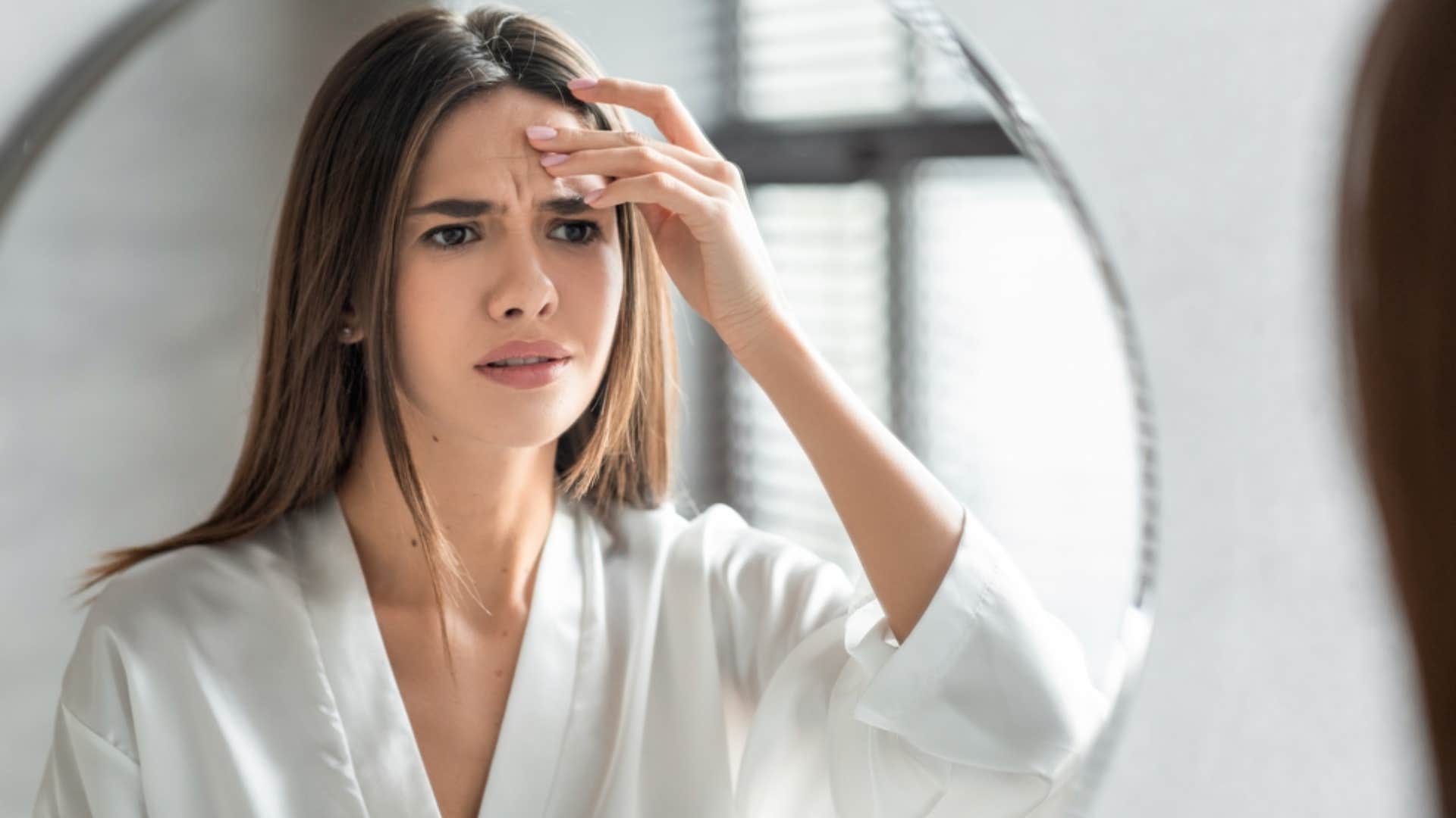 unhappy woman looking at herself in the mirror