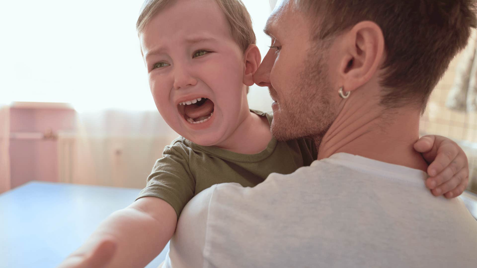father holding screaming child