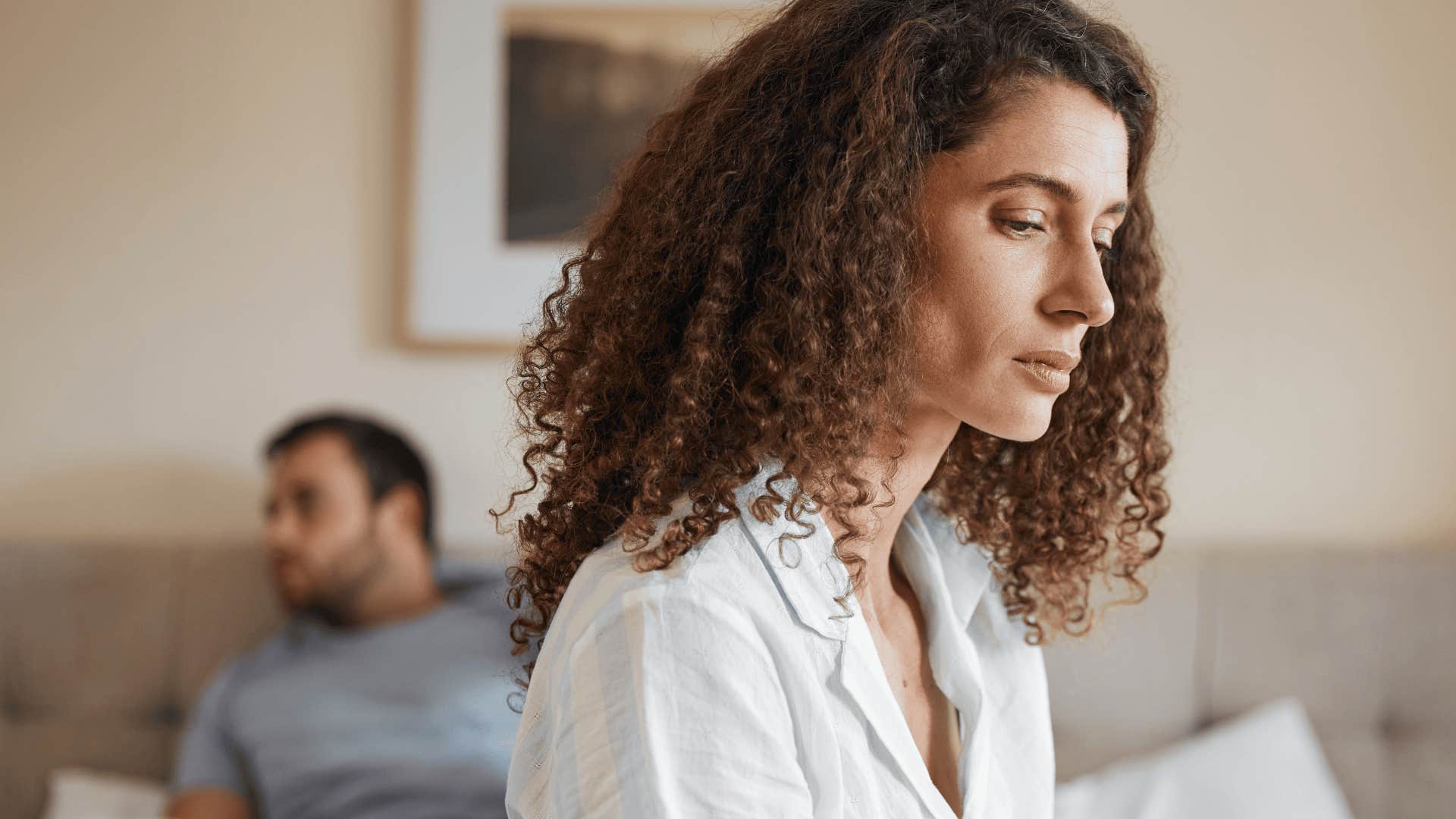 woman sitting on bed while her spouse's battery is low