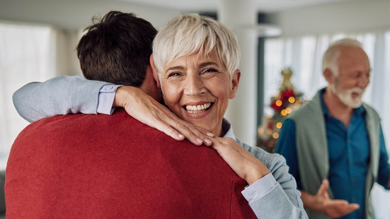senior parent hugging her adult son at home