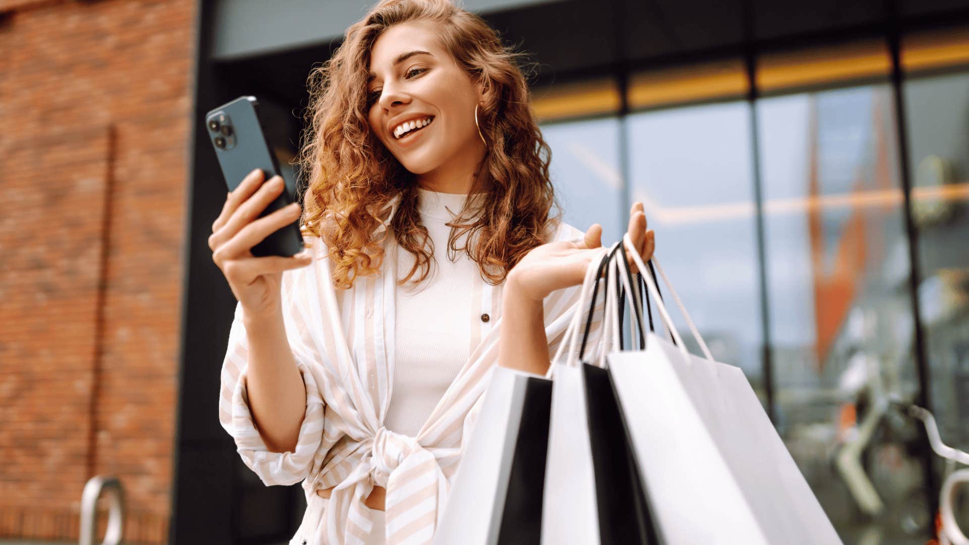 Woman smiling and texting on her phone while shopping