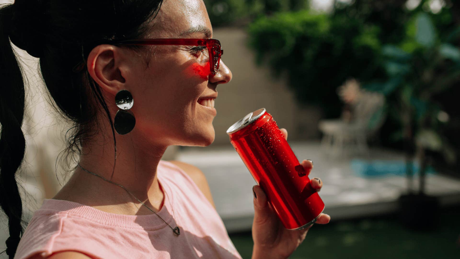 Woman smiling and drinking from a soda can