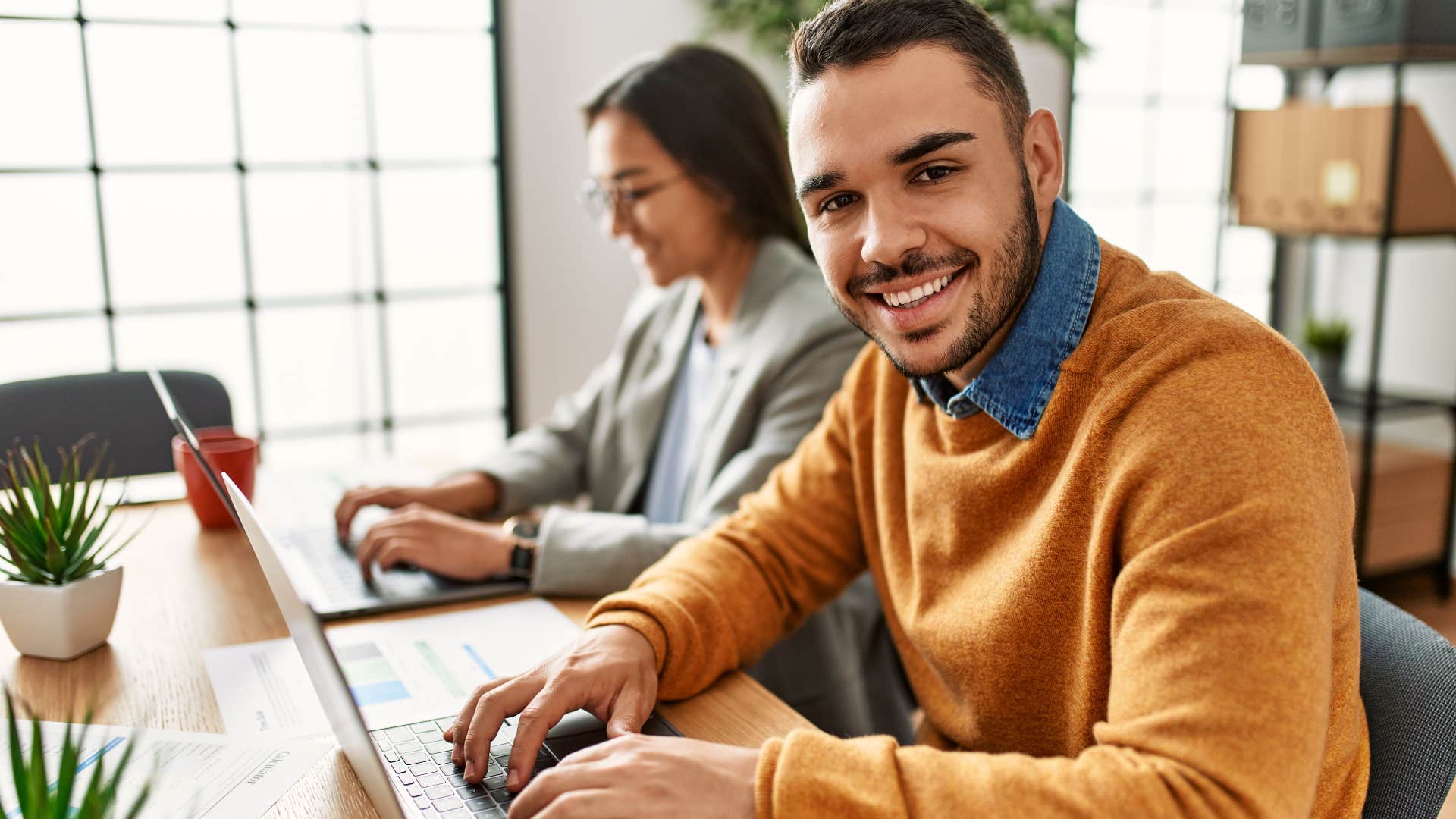 young man smiling while working on his laptop