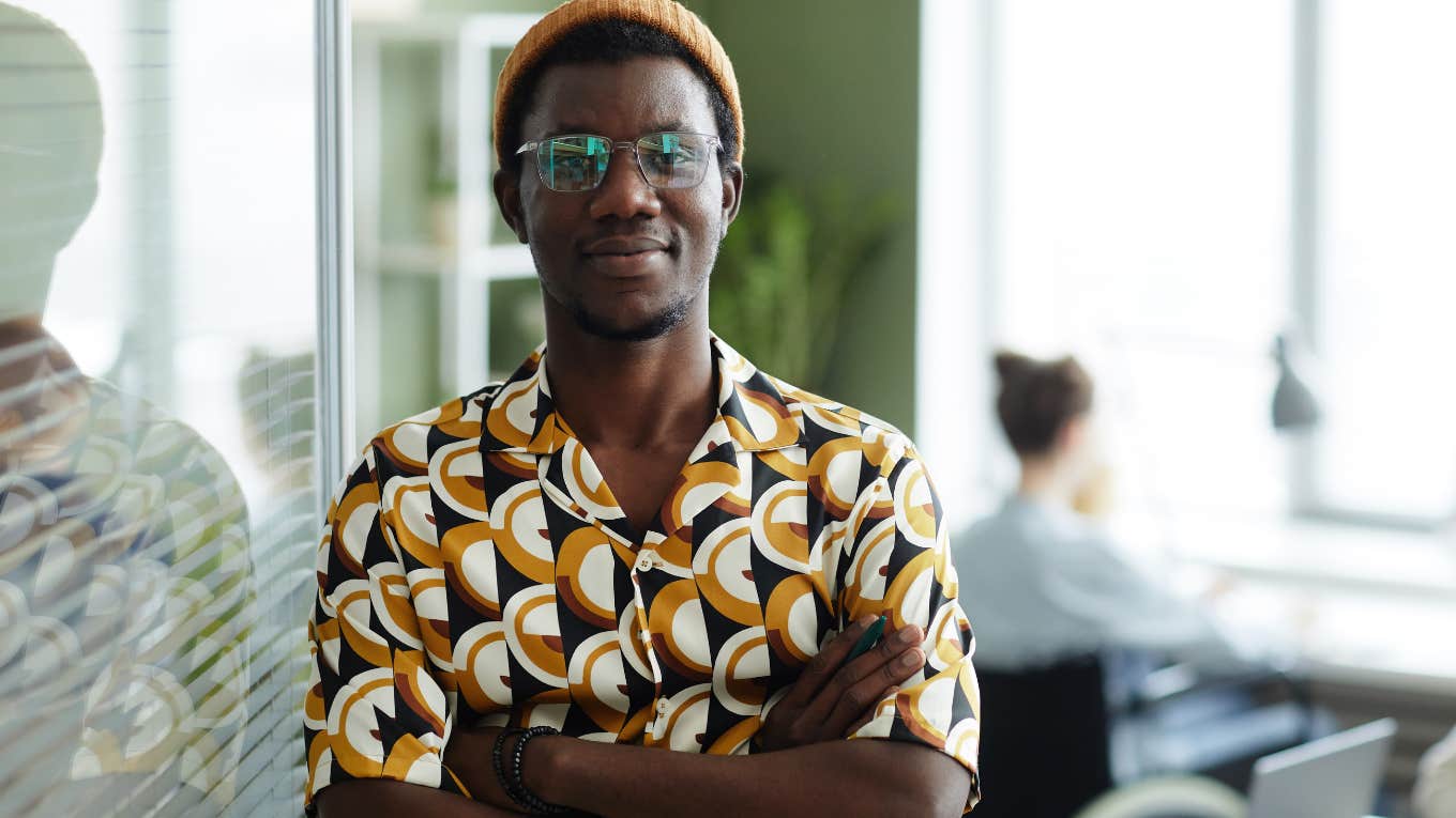 Things Gen Z Does At Work That Drive Their Boomer Bosses Crazy professional Gen Z man smiling in an office