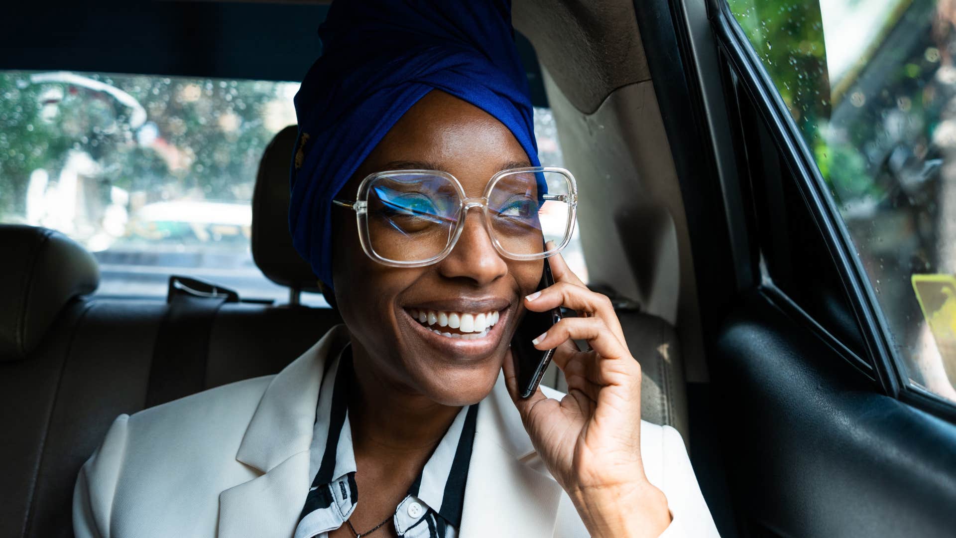 woman smiling in a car talking on the phone