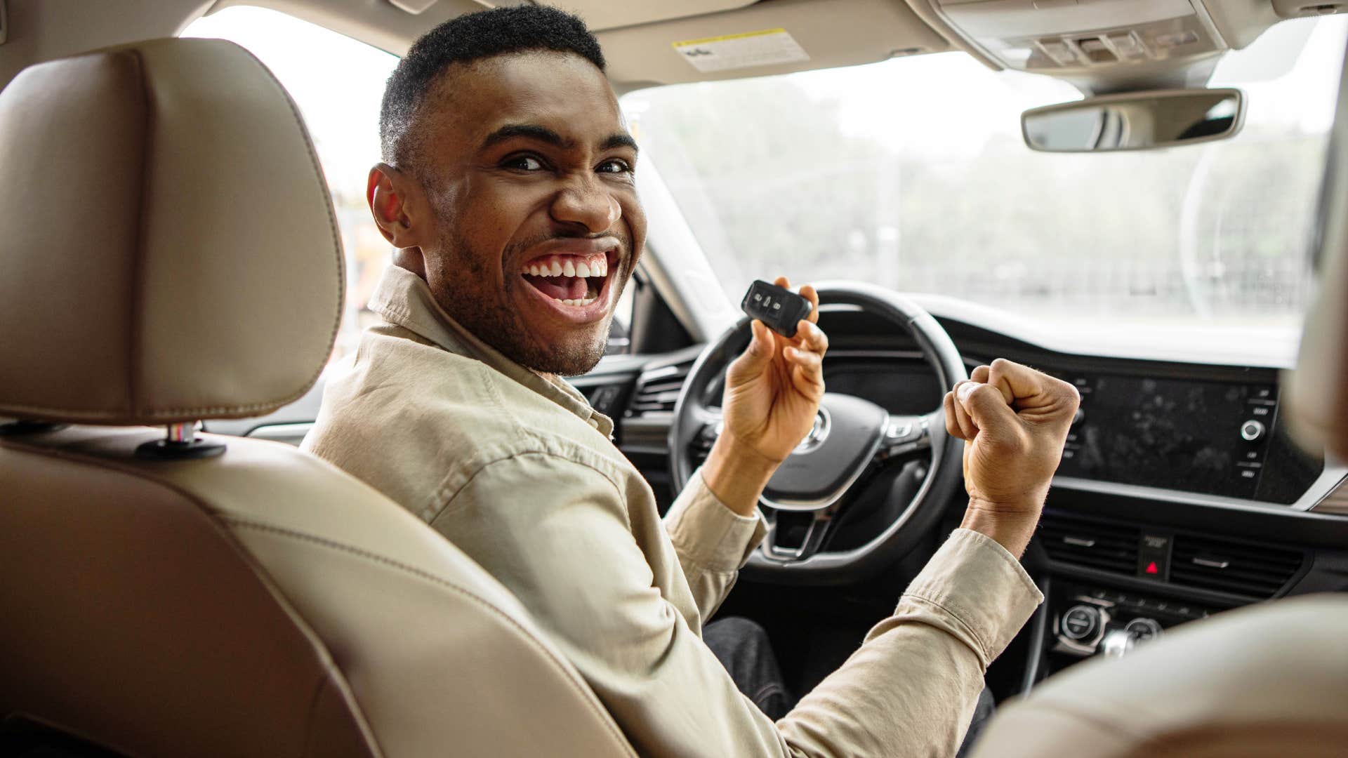 man smiling and sitting in his new car
