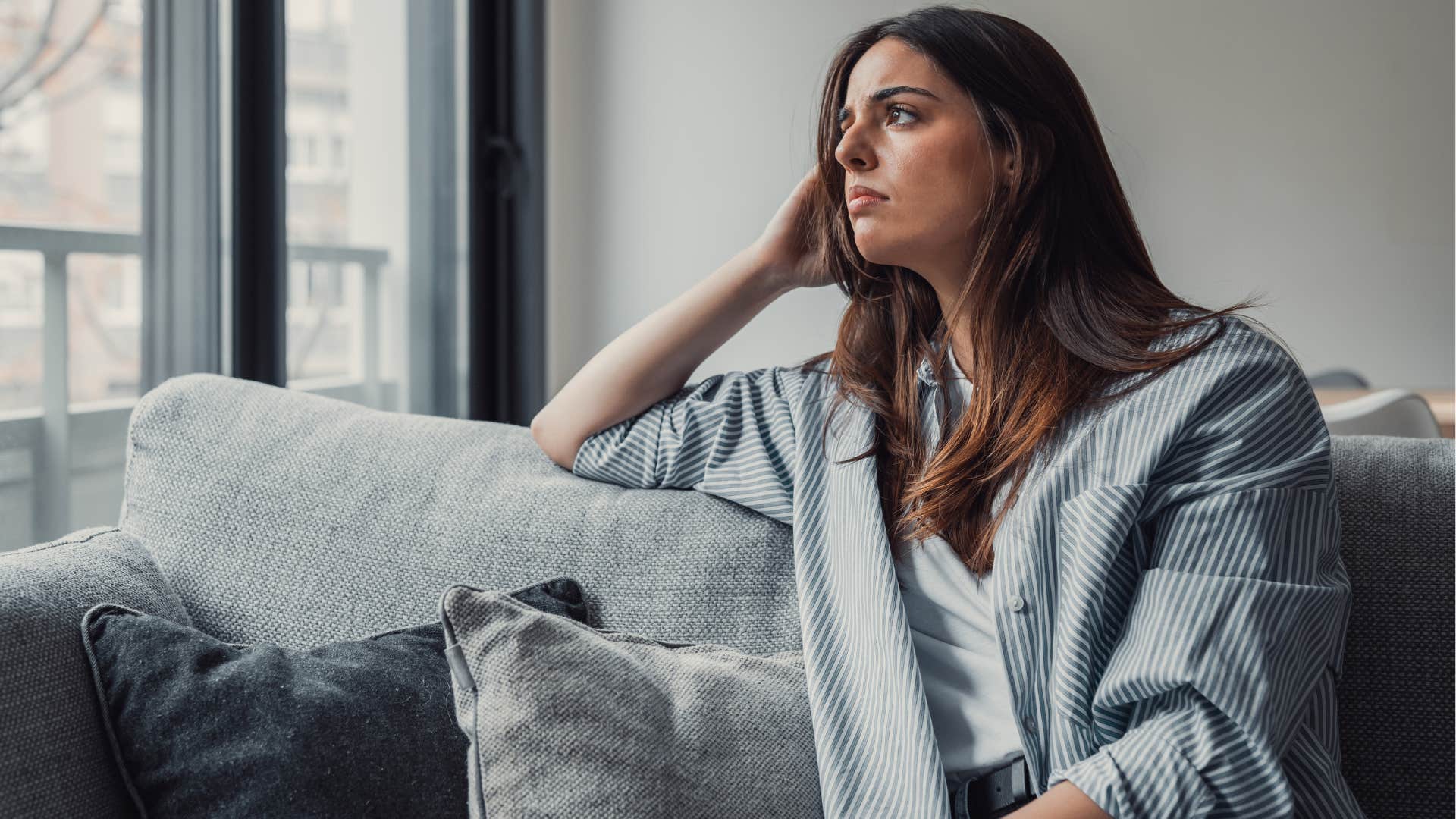 sad Gen Z woman looking out a window