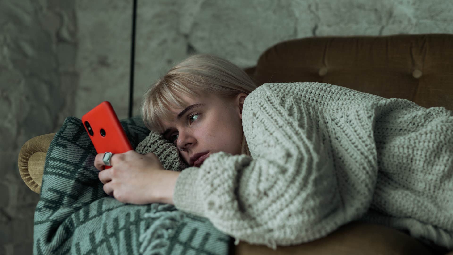 gen z woman lying on couch glued to phone
