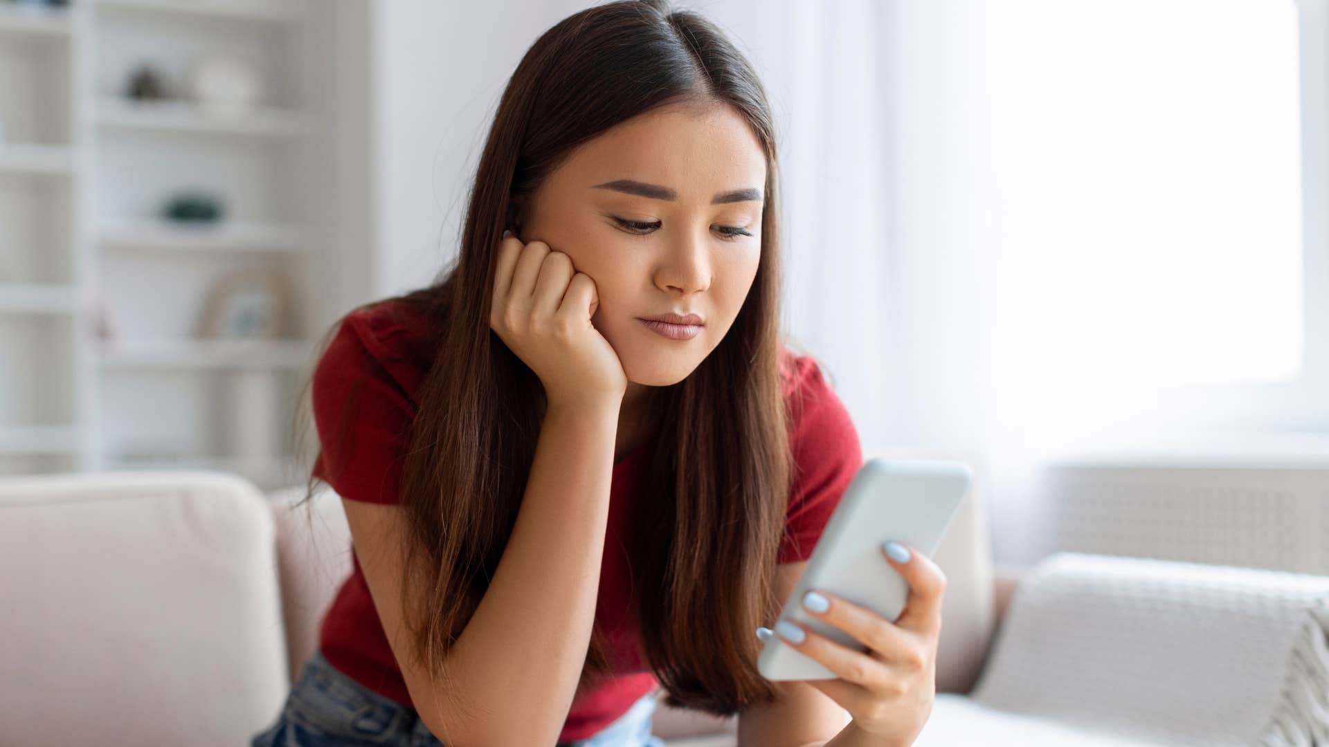 sad gen z woman reading the news on her phone
