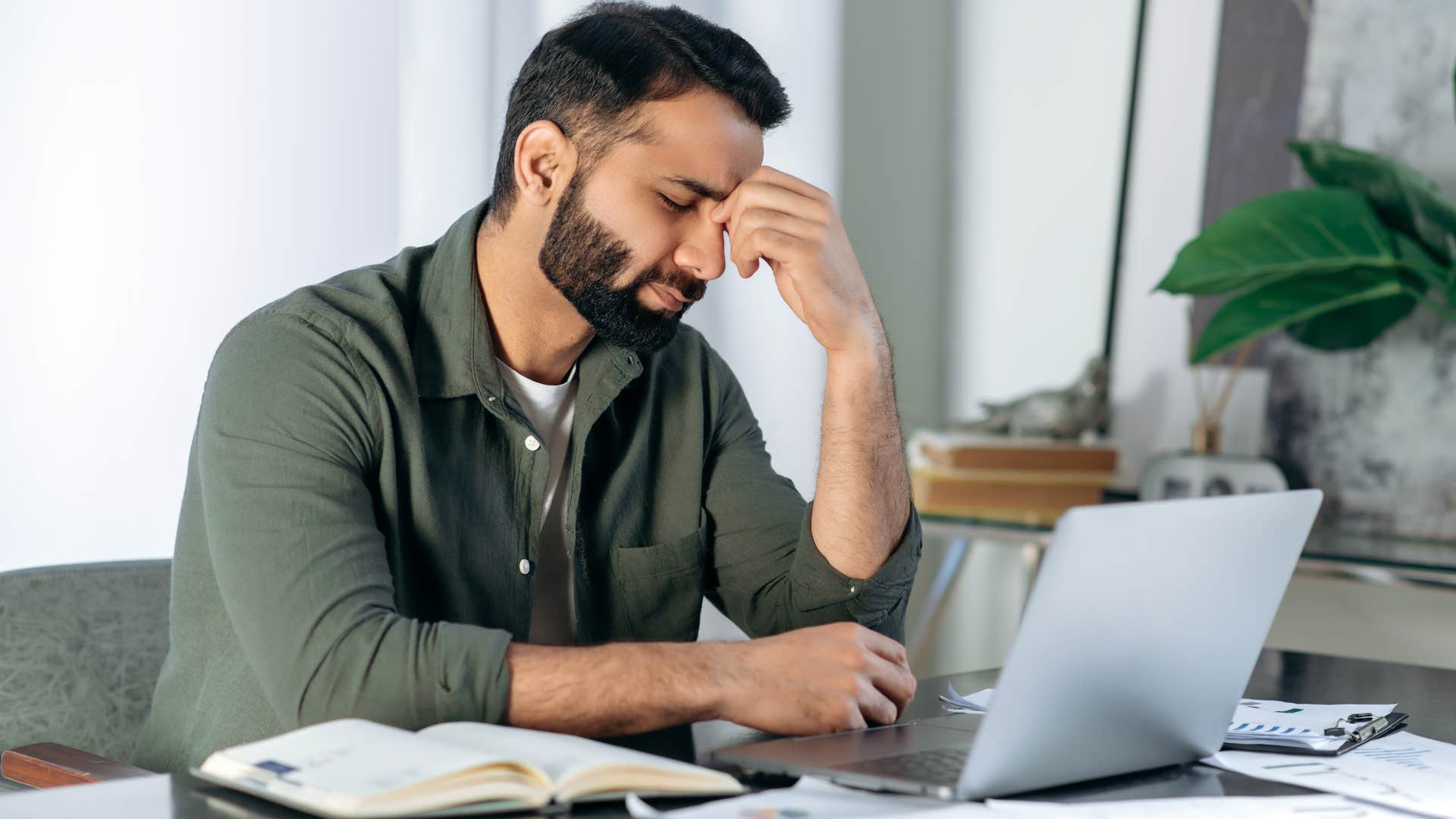 stressed man holding his head feeling overworked