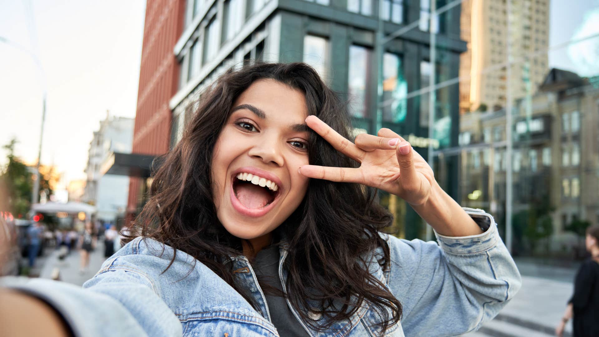 gen z woman smiling making peace sign