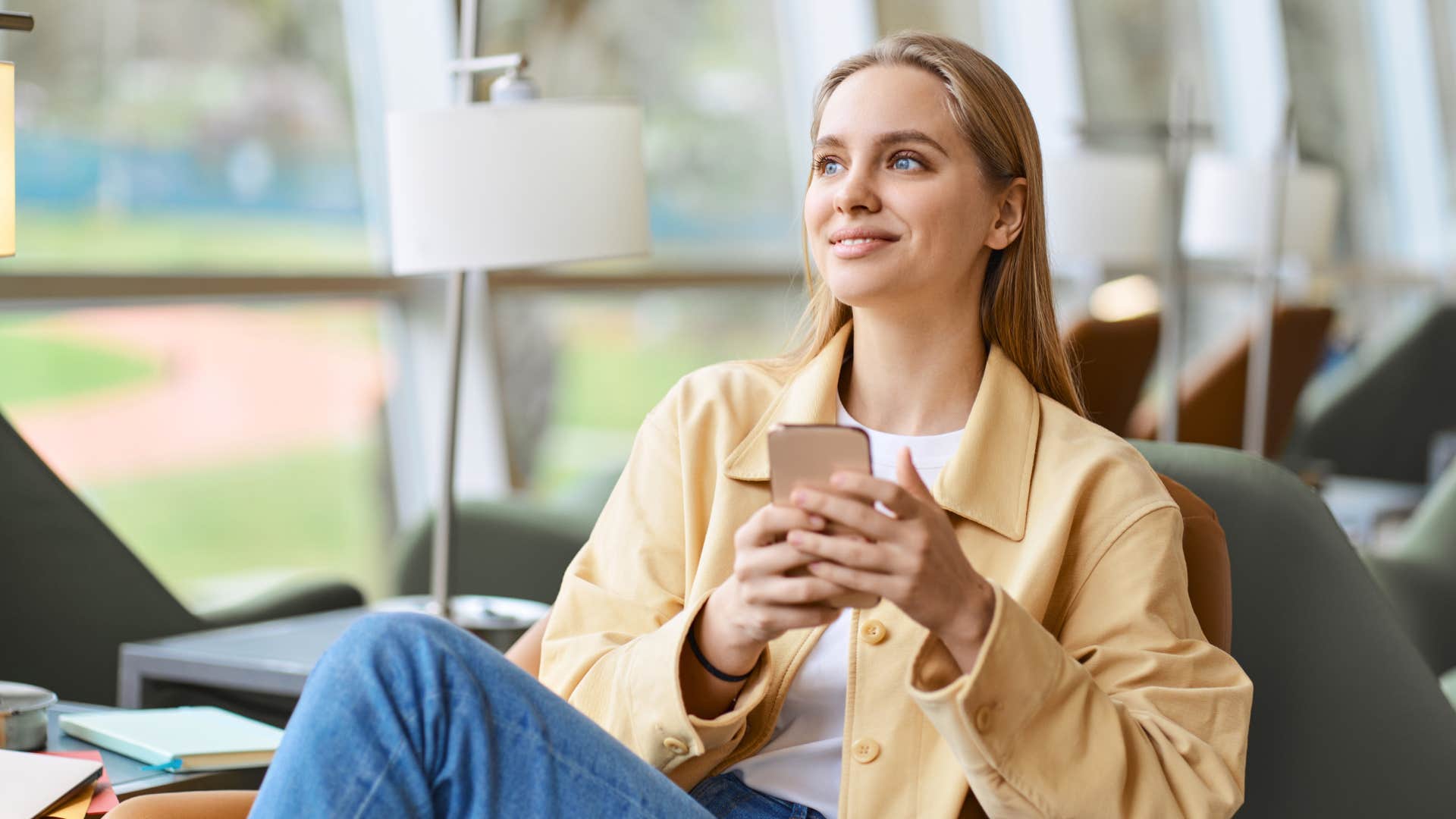 gen z woman smiling holding her phone