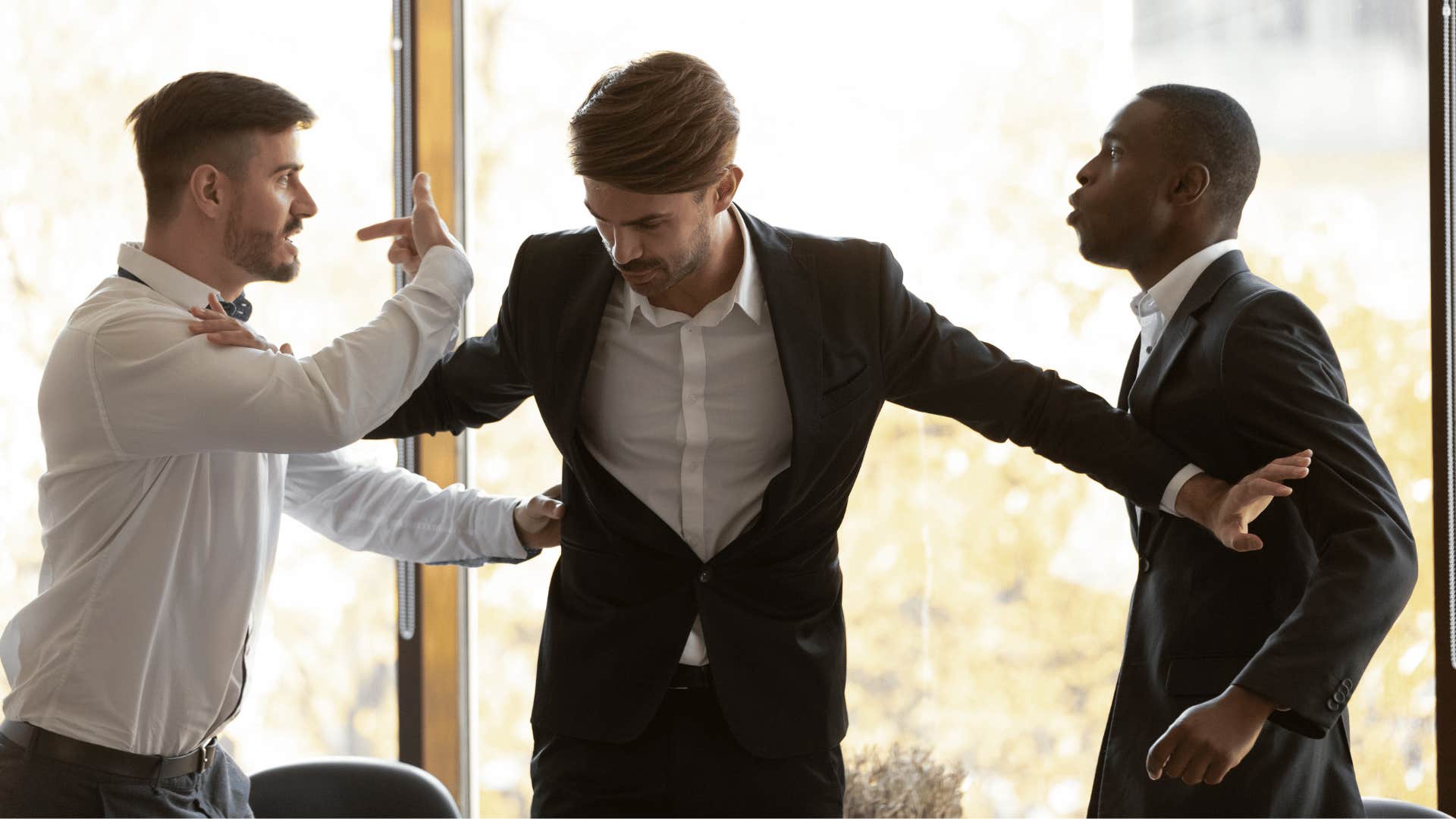 One man steps between two fighting men who think competition mattes