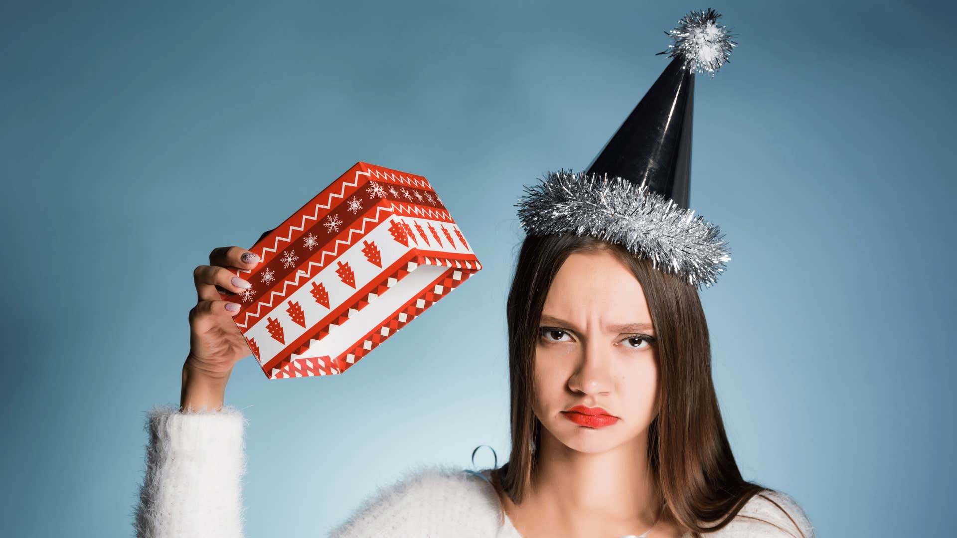 Dissatisfied woman holds up expensive gift that means nothing to her
