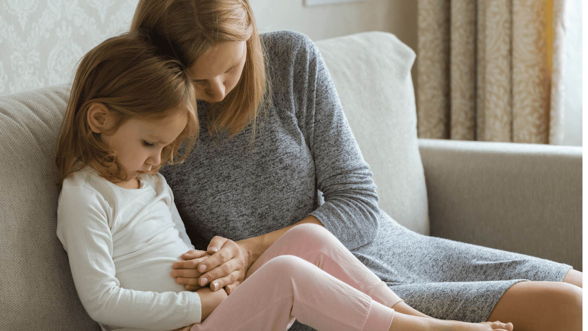 mom touching young daughters stomach