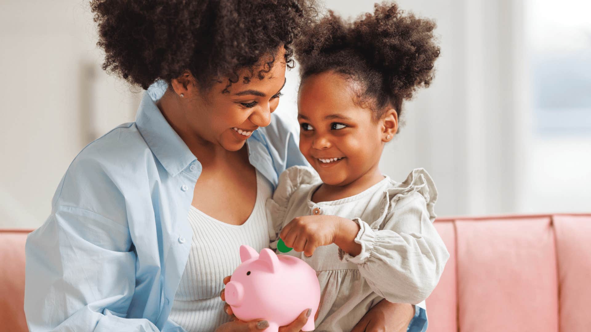 mom teaching daughter to save money in piggybank