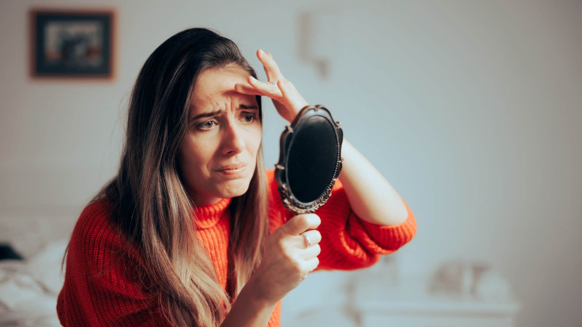 millennial woman looking at wrinkles in the mirror
