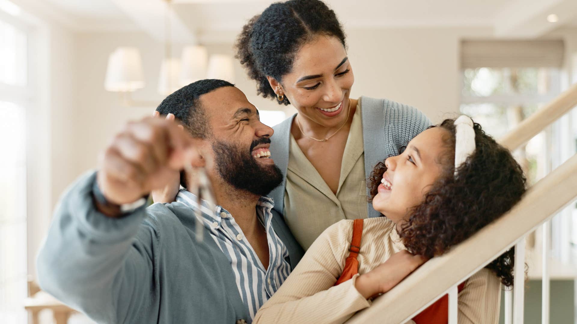 Young family smiling and hugging on the stairs at home