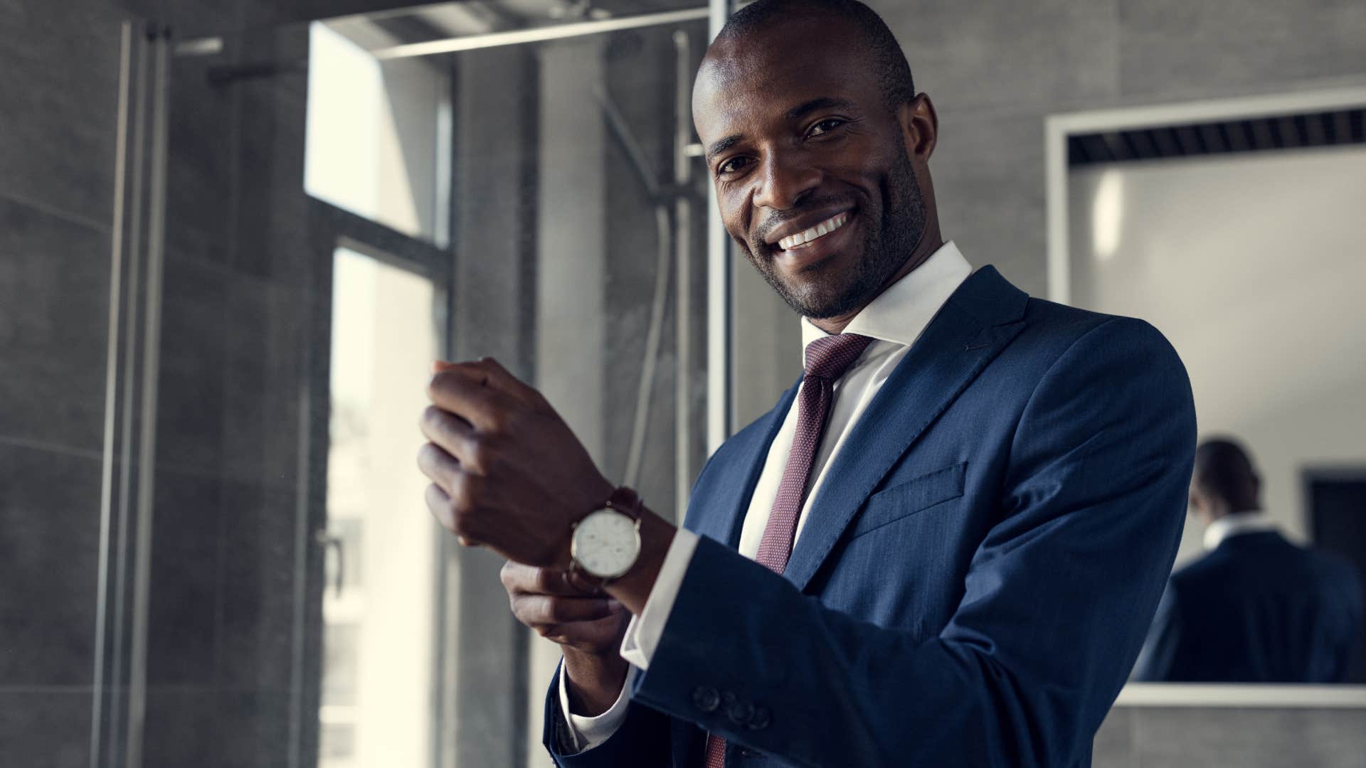 Professional man smiling and putting on a watch