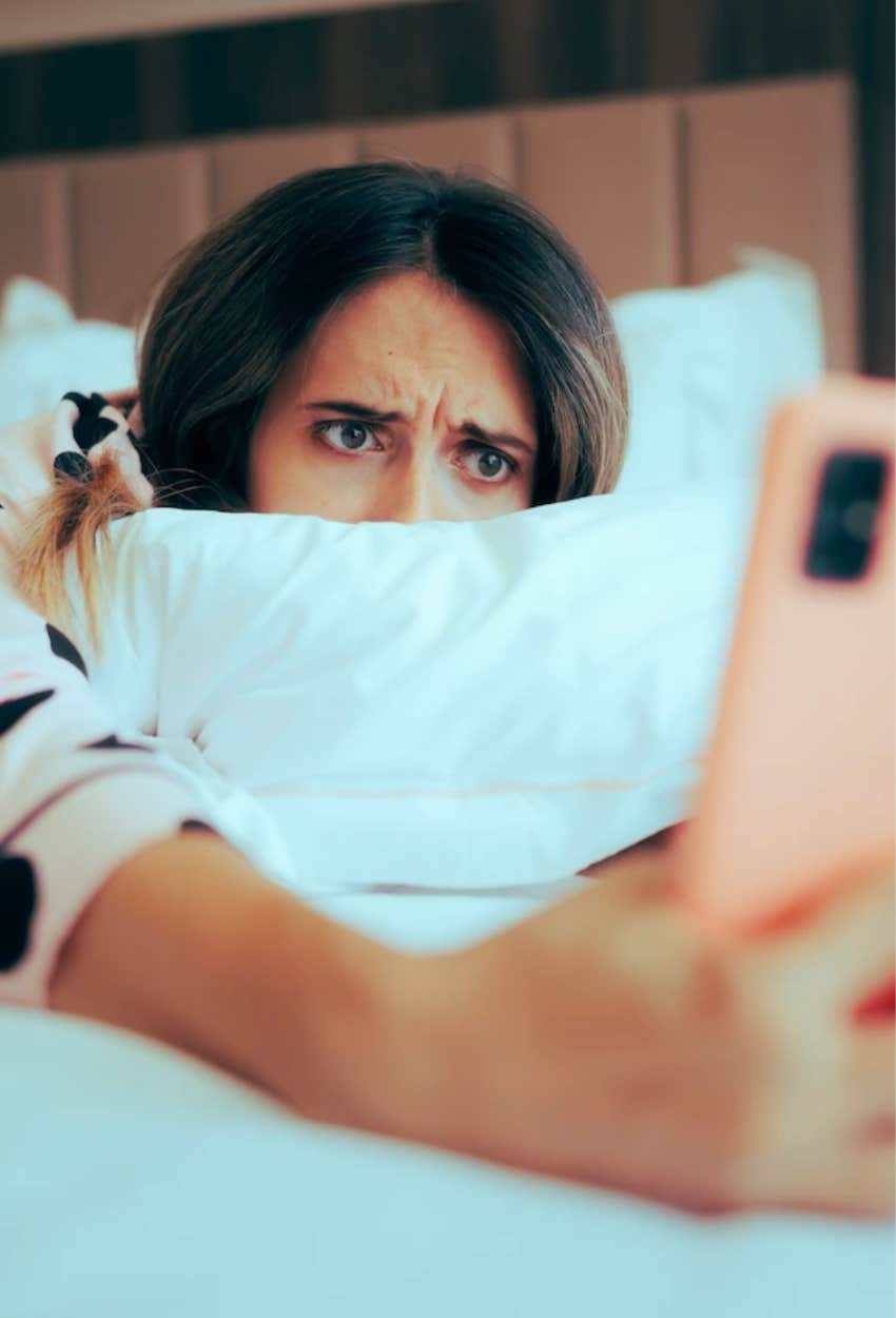 Woman with broken heart staring at her phone trying to keep tabs on her ex