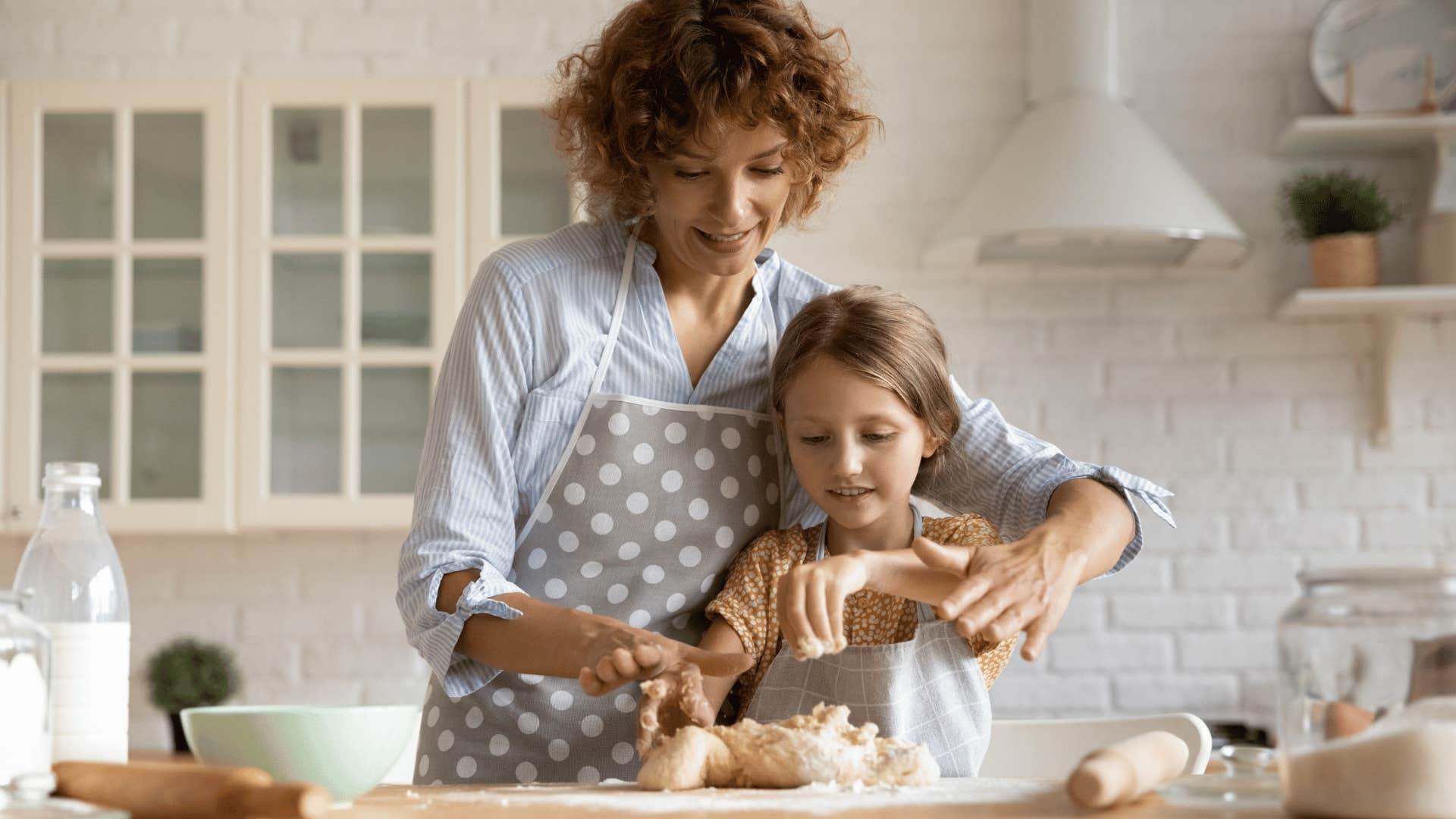 nanny kneading dough with child she's babysitting