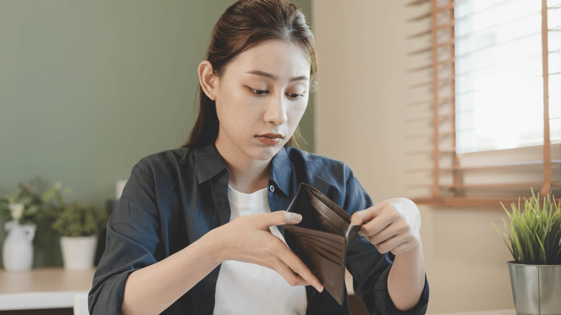 woman looking in empty wallet no money